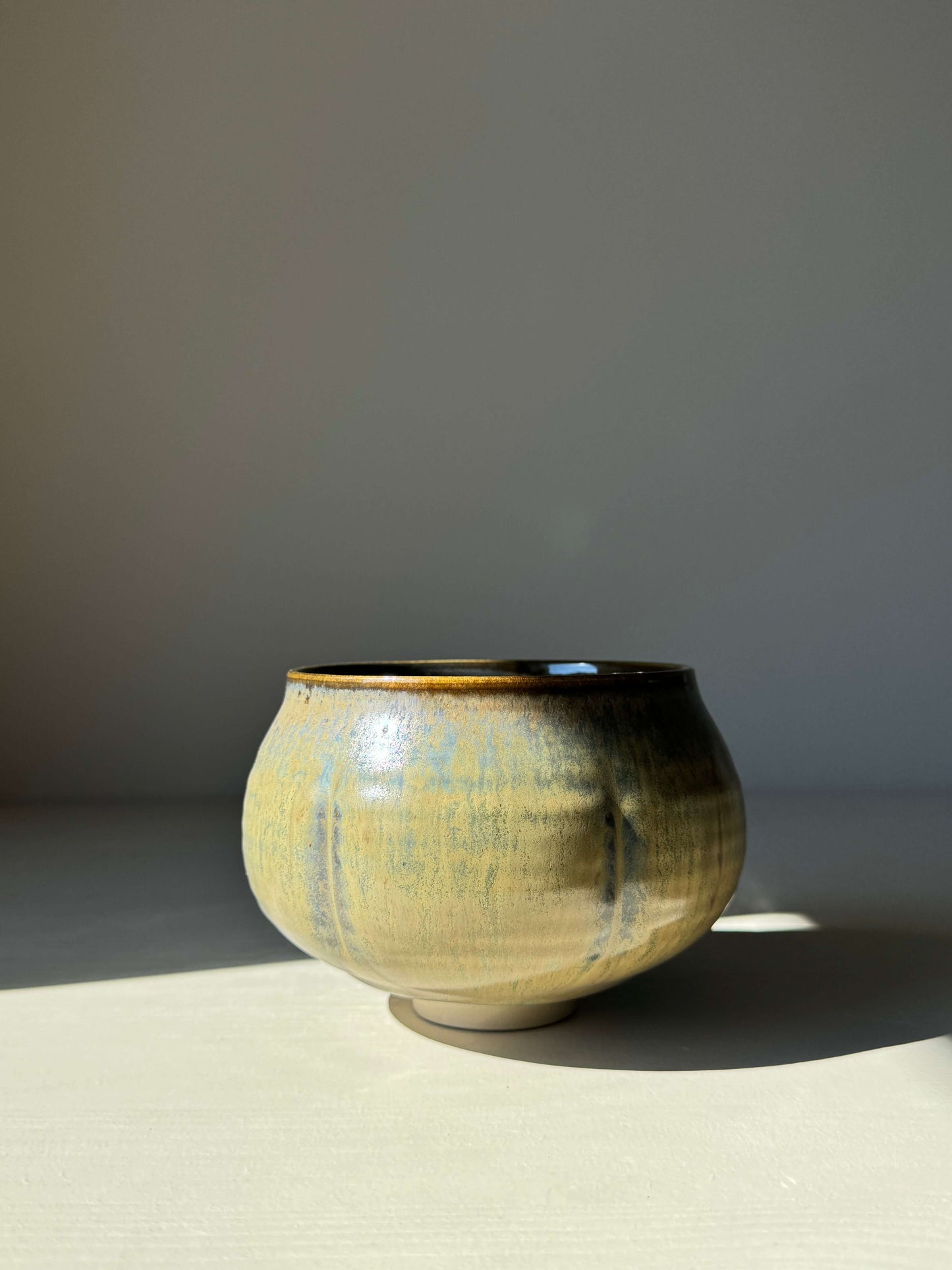 Sabi Black Matcha Bowl with golden ochre tones and soft blue-green accents, inspired by Japanese wabi-sabi aesthetic.