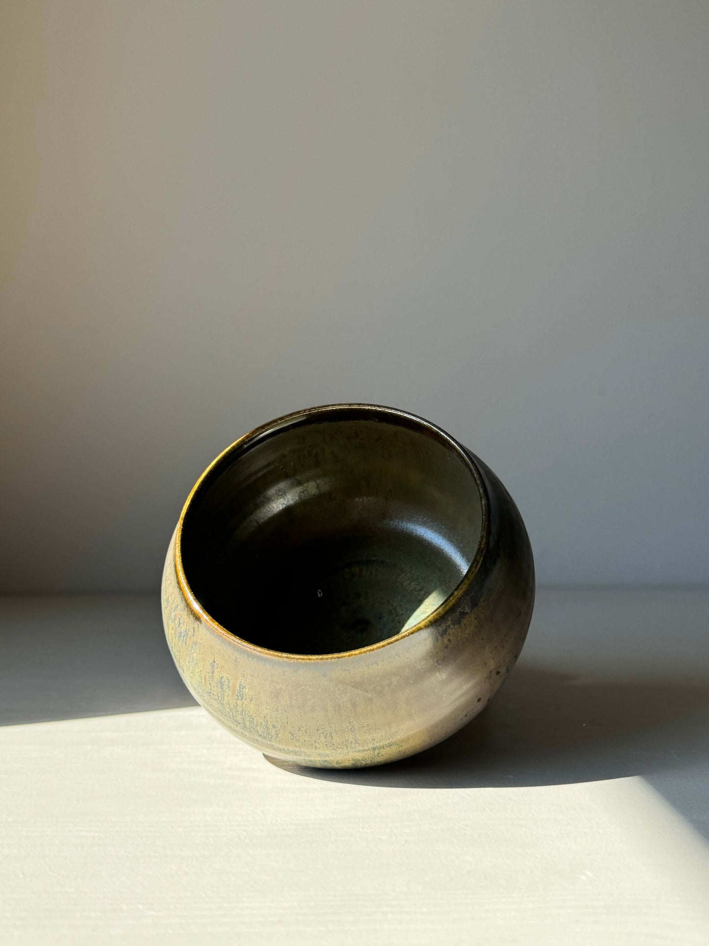 Matcha bowl with Sabi Black glaze, featuring golden ochre tones and blue-green hues, inspired by wabi-sabi aesthetics.