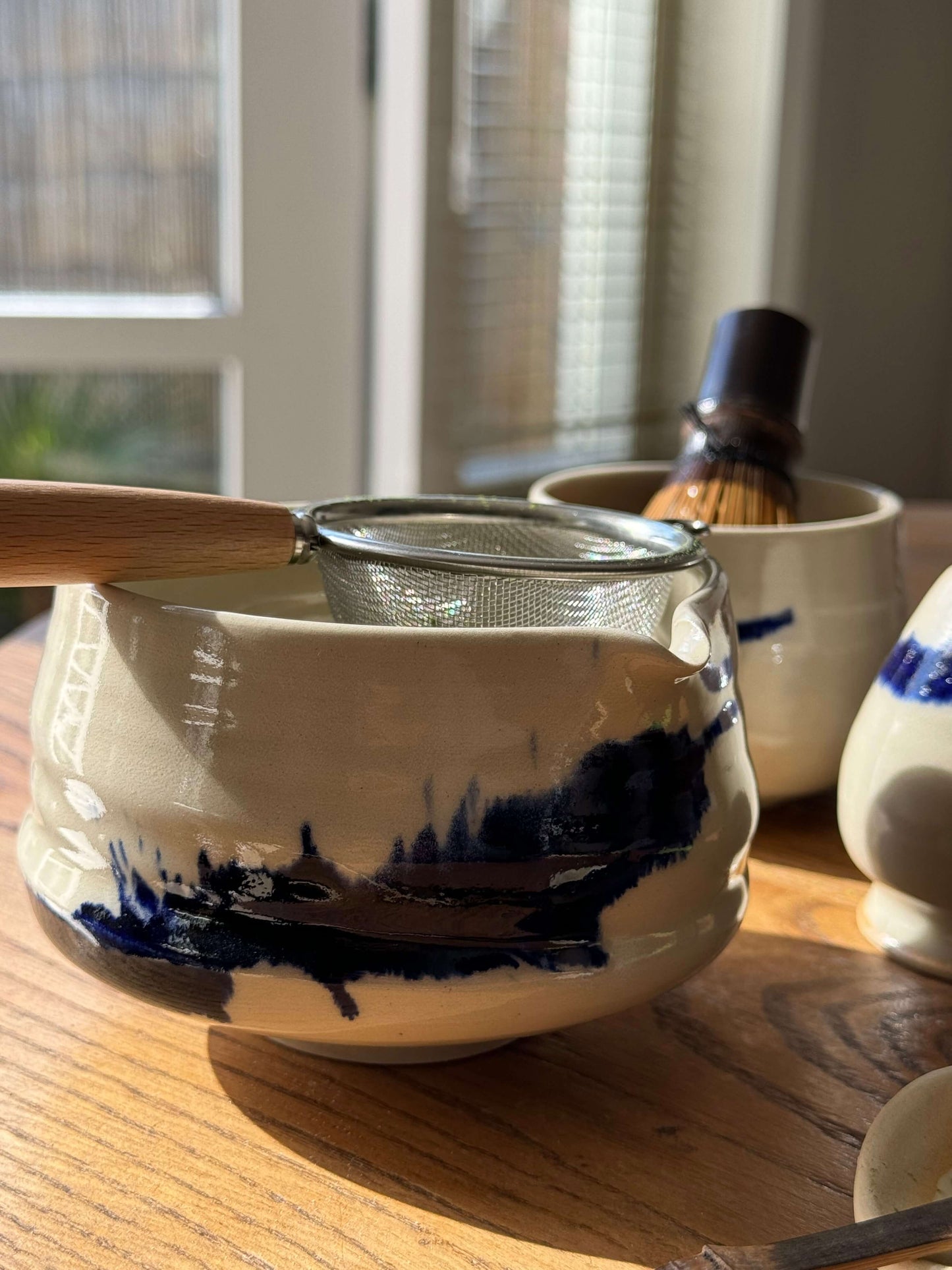 Handmade Gosu Series matcha bowl with spout, featuring unique cobalt blue splashes on clear glaze, perfect for whisking matcha.