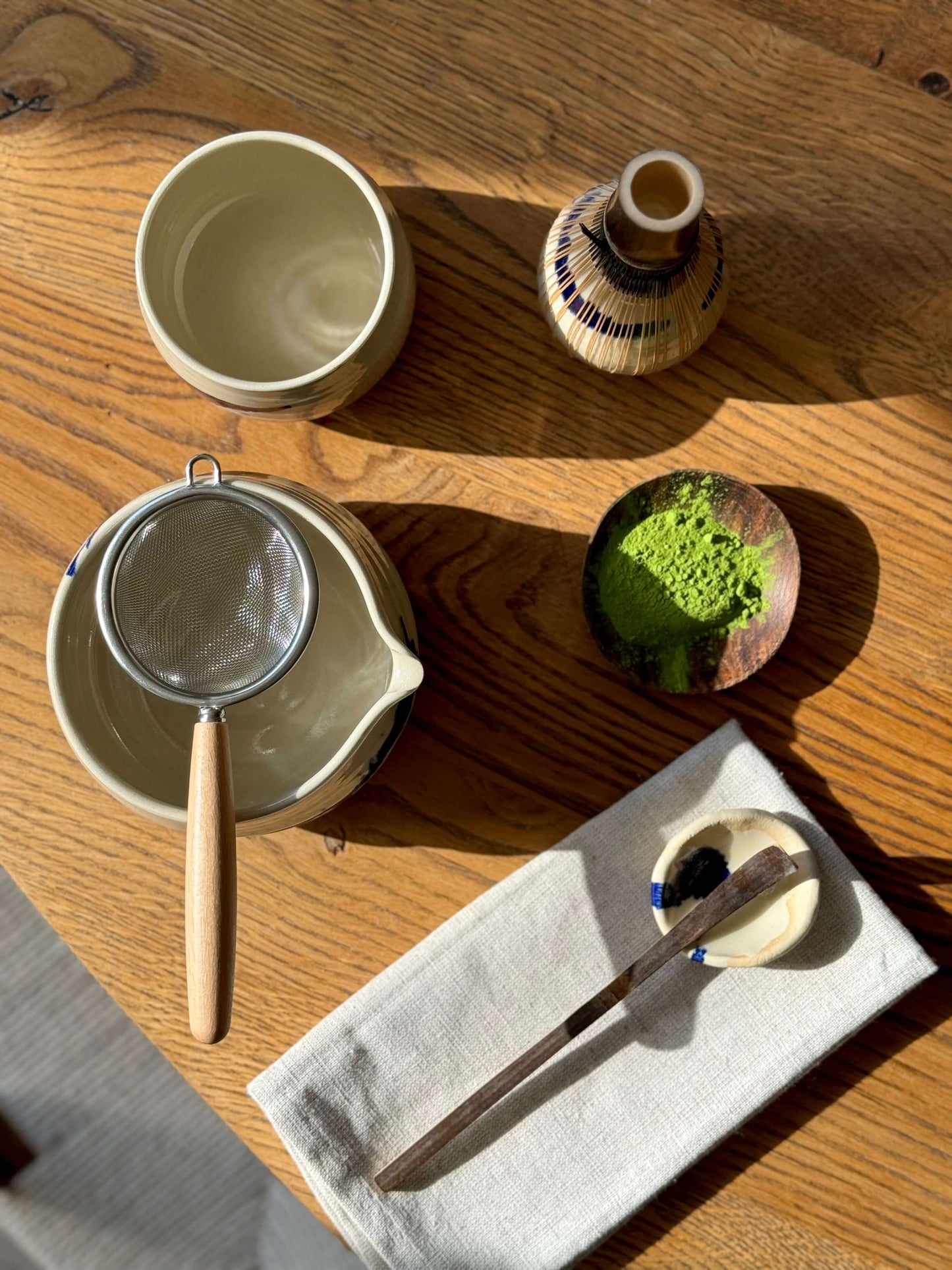 Overhead view of Gosu Series Matcha Bowl with spout, sieve, matcha powder, and tea accessories on a wooden table.