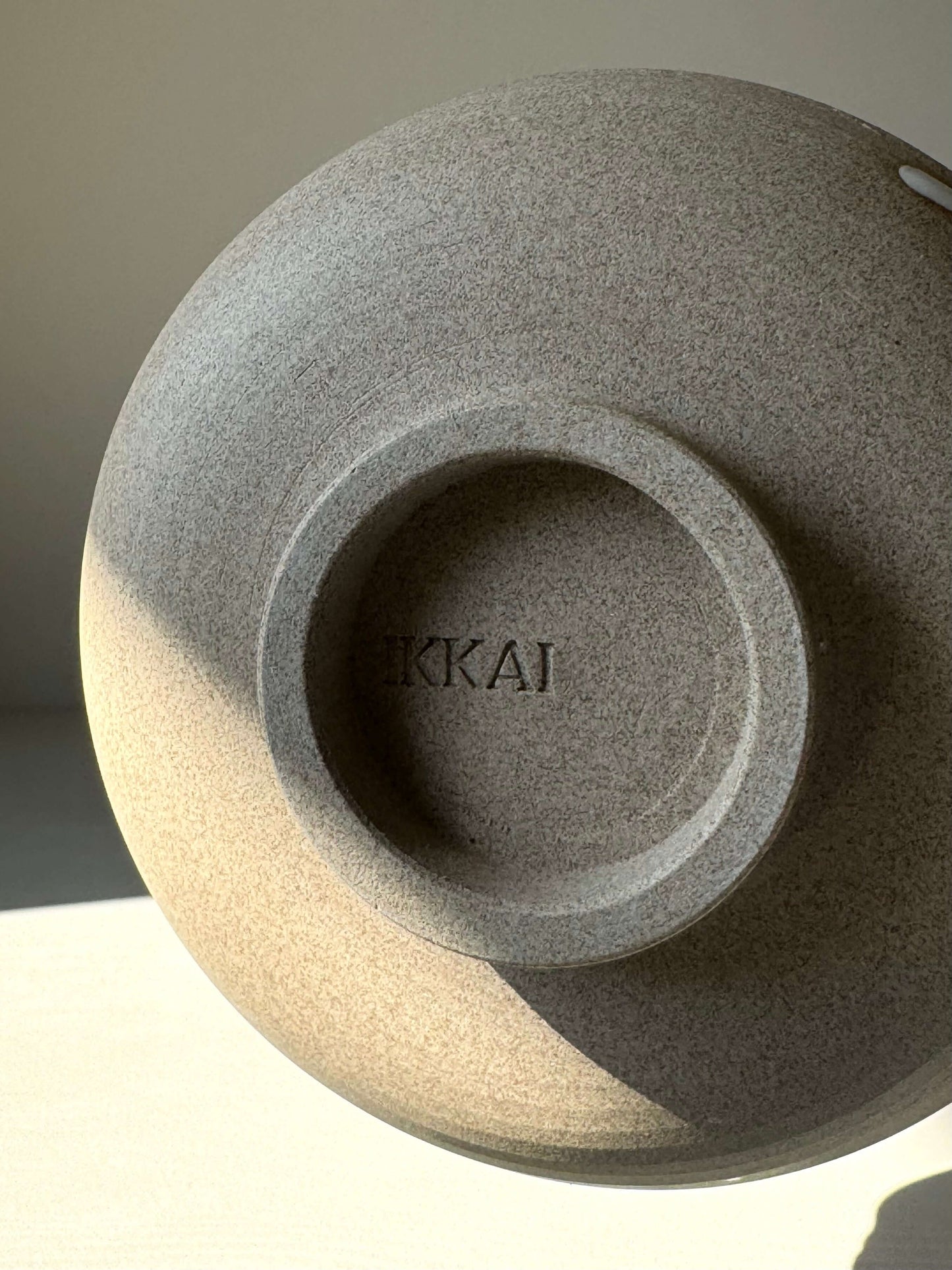 Close-up of a handcrafted Matcha bowl in toffee clay with "IKKAI" inscribed, showcasing artisanal craftsmanship and natural texture.