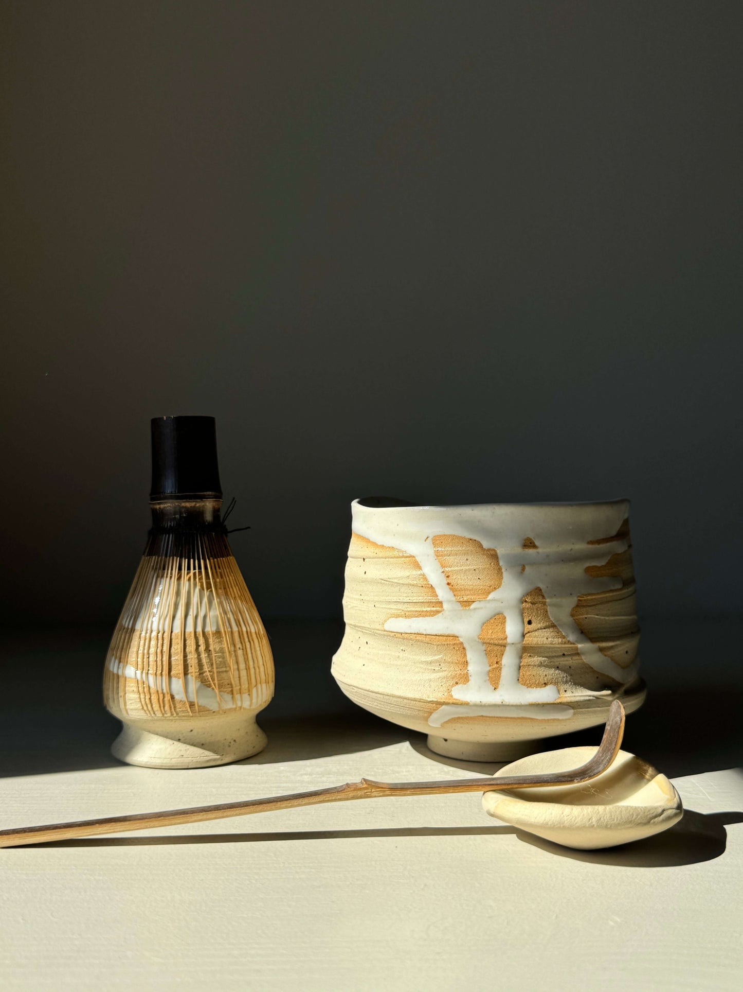 Matcha tea set with a whisk holder, bowl, and spoon in half glossy white glaze on speckled stoneware.