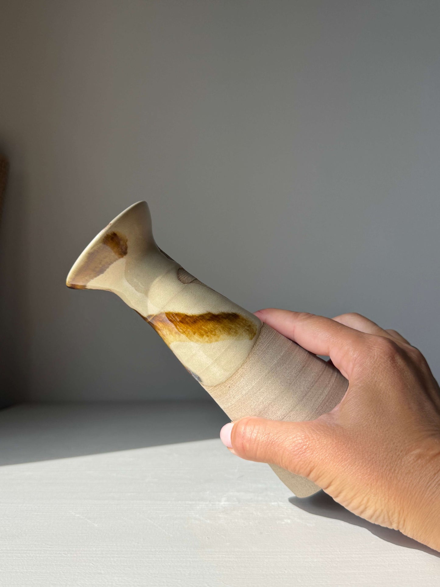 Hand holding Medium Vase – Inyo Series #04, a handmade ceramic with unique glaze patterns, showcasing a tall, flared design.
