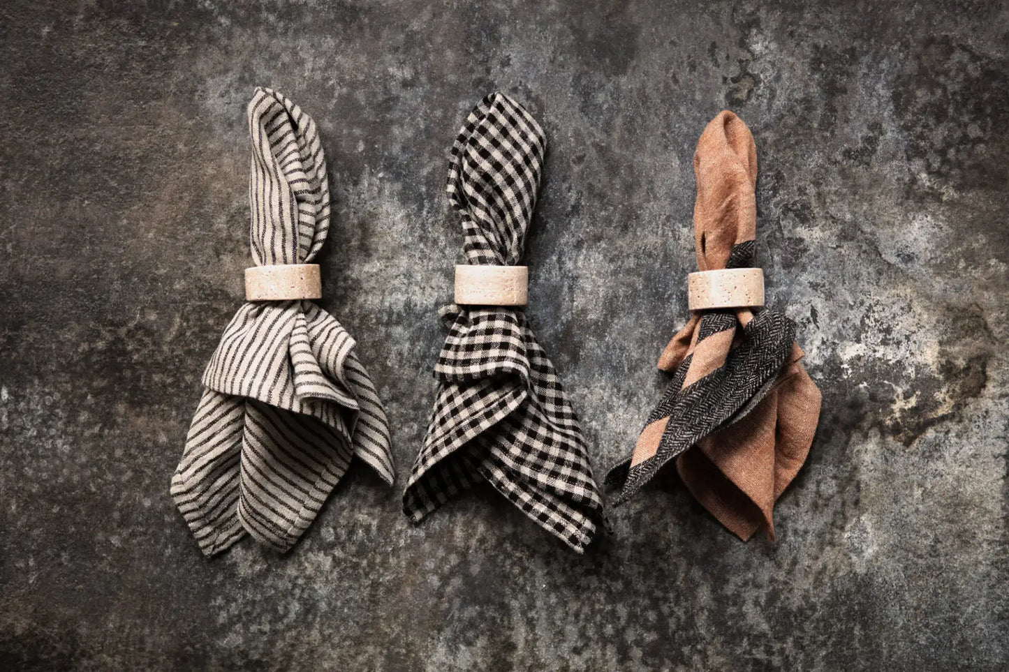 Three folded striped linen napkins with natural texture on rustic background.