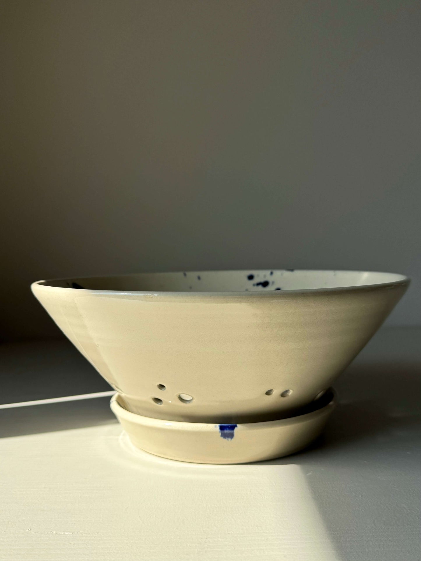 Sculptural berry bowl with cobalt blue splashes from Gosu Series, ideal for rinsing fresh fruit, paired with a matching drip plate.