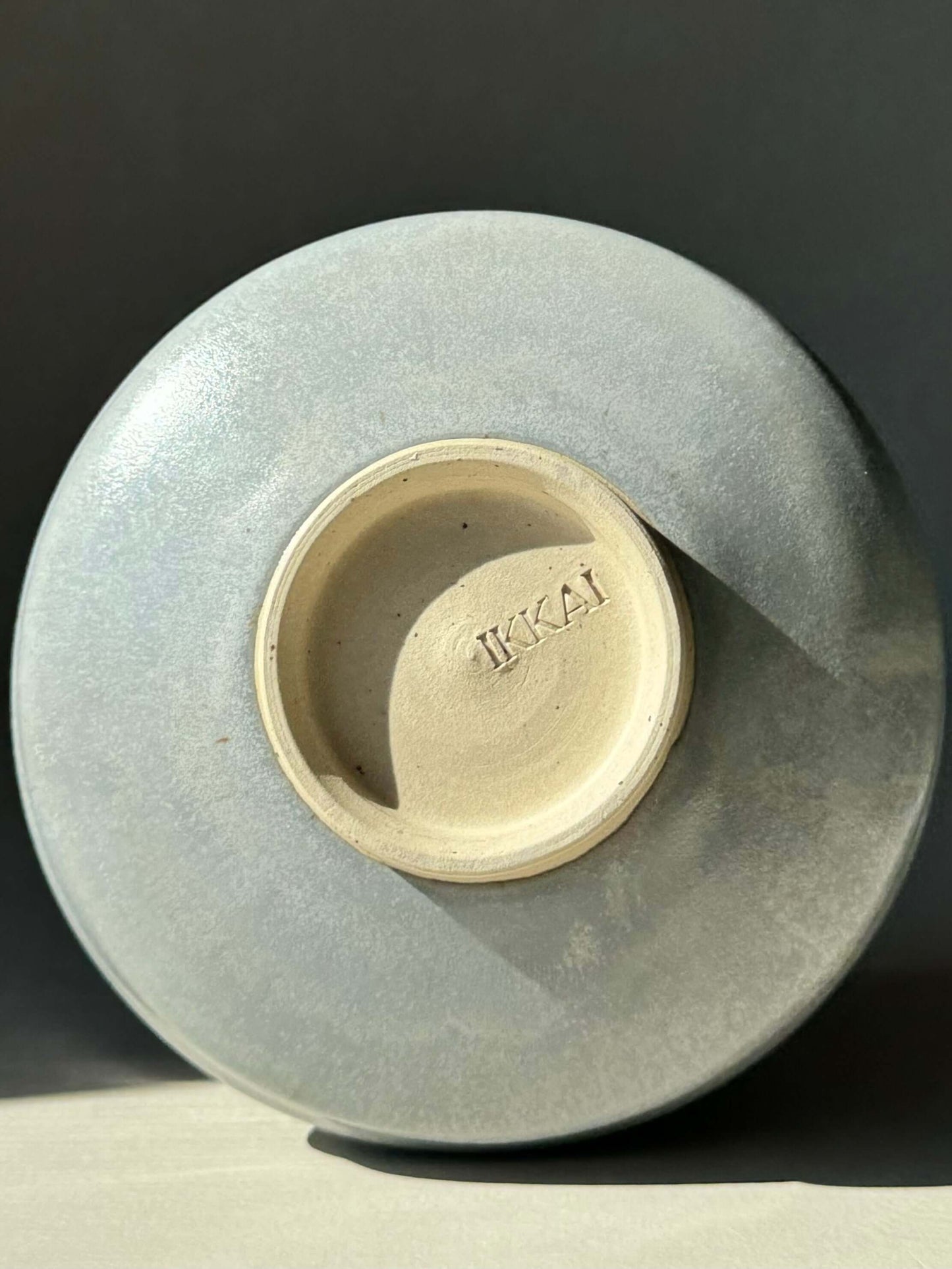Bottom view of a matcha bowl in sky blue glaze with "IKKAI" imprint.