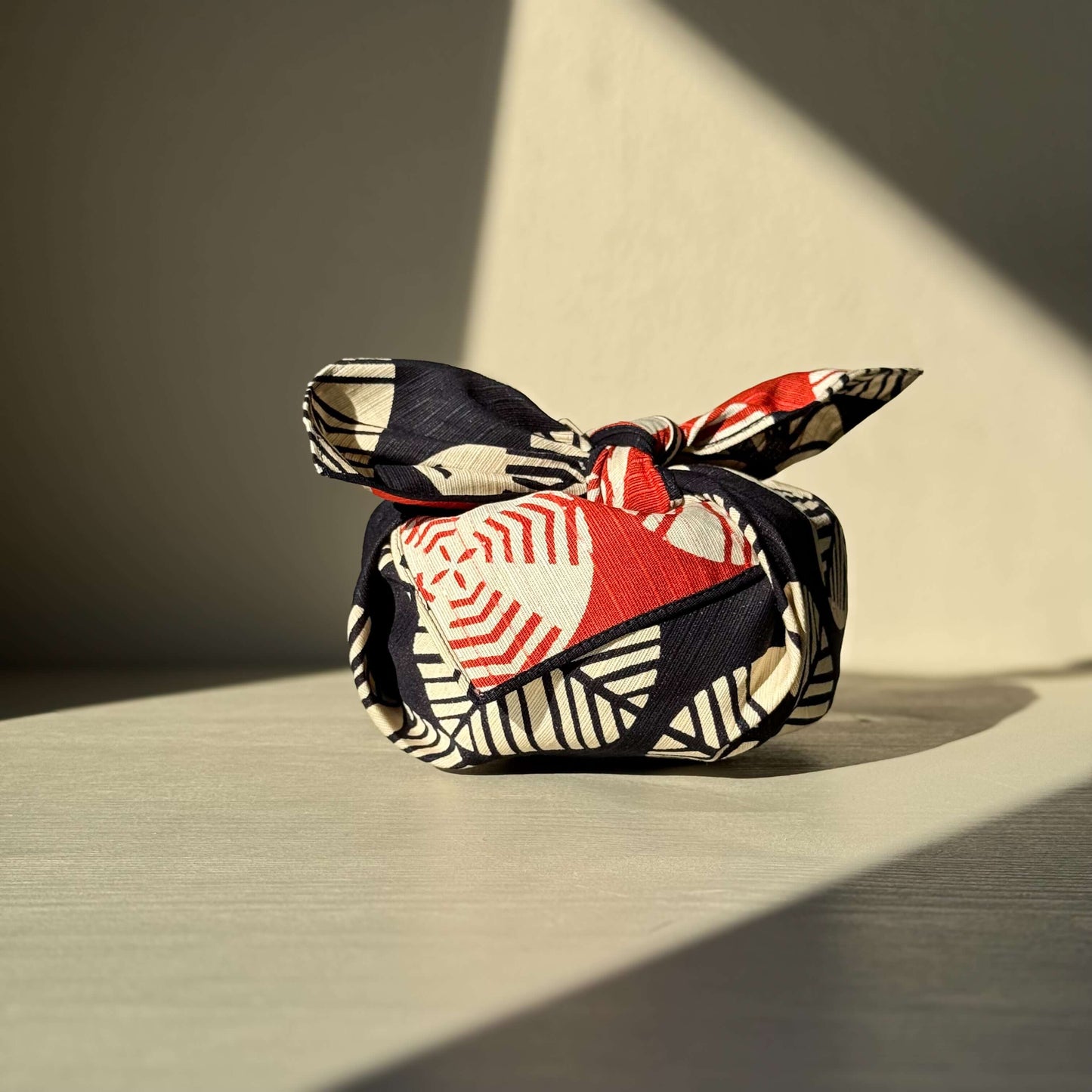 Small Furoshiki - Navy Blue & Red wrapping a package, handmade ceramic pattern, representing longevity in Japanese culture.