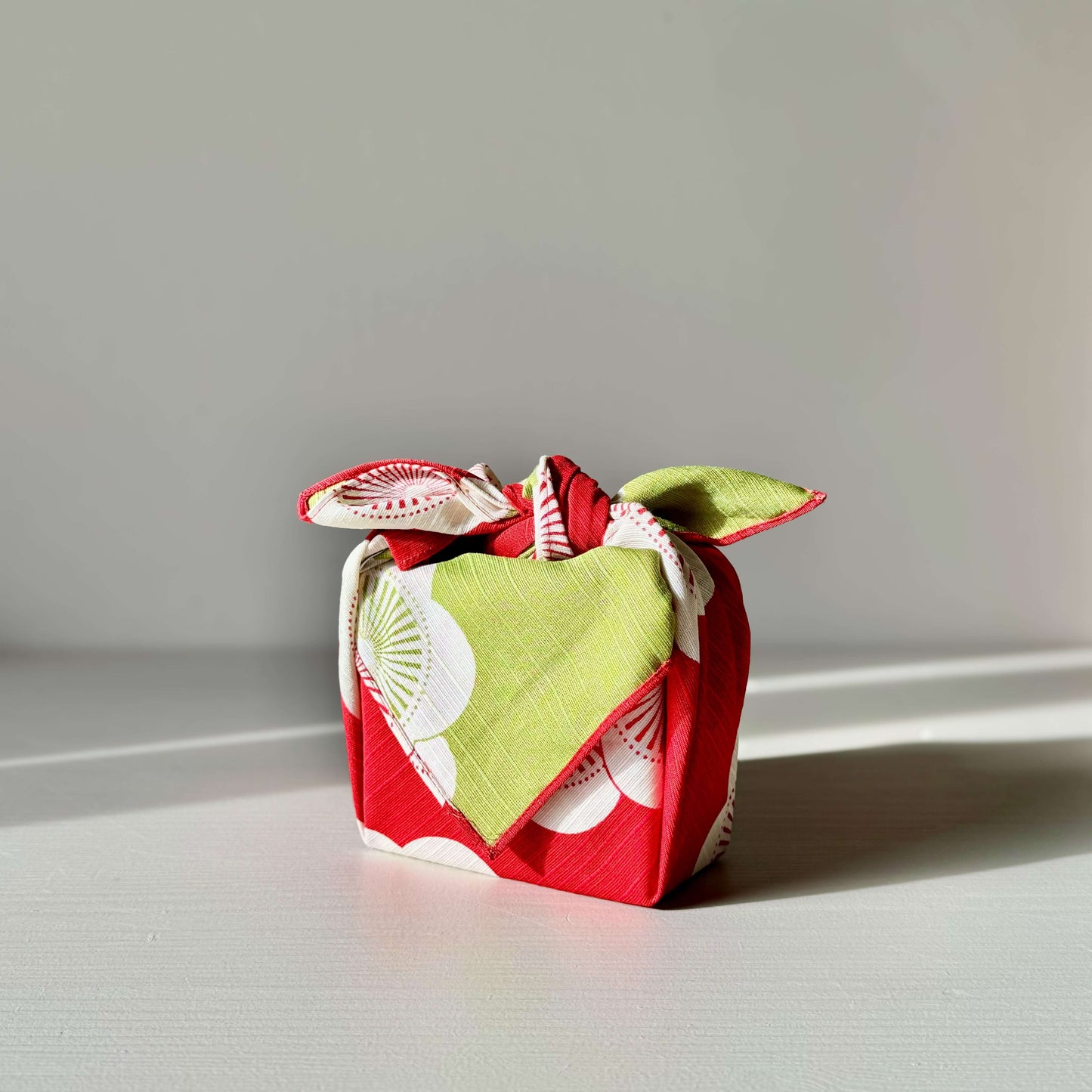 Red and green small furoshiki gift wrap featuring plum blossom design, symbolizing happiness and resilience. Eco-friendly reusable wrap.