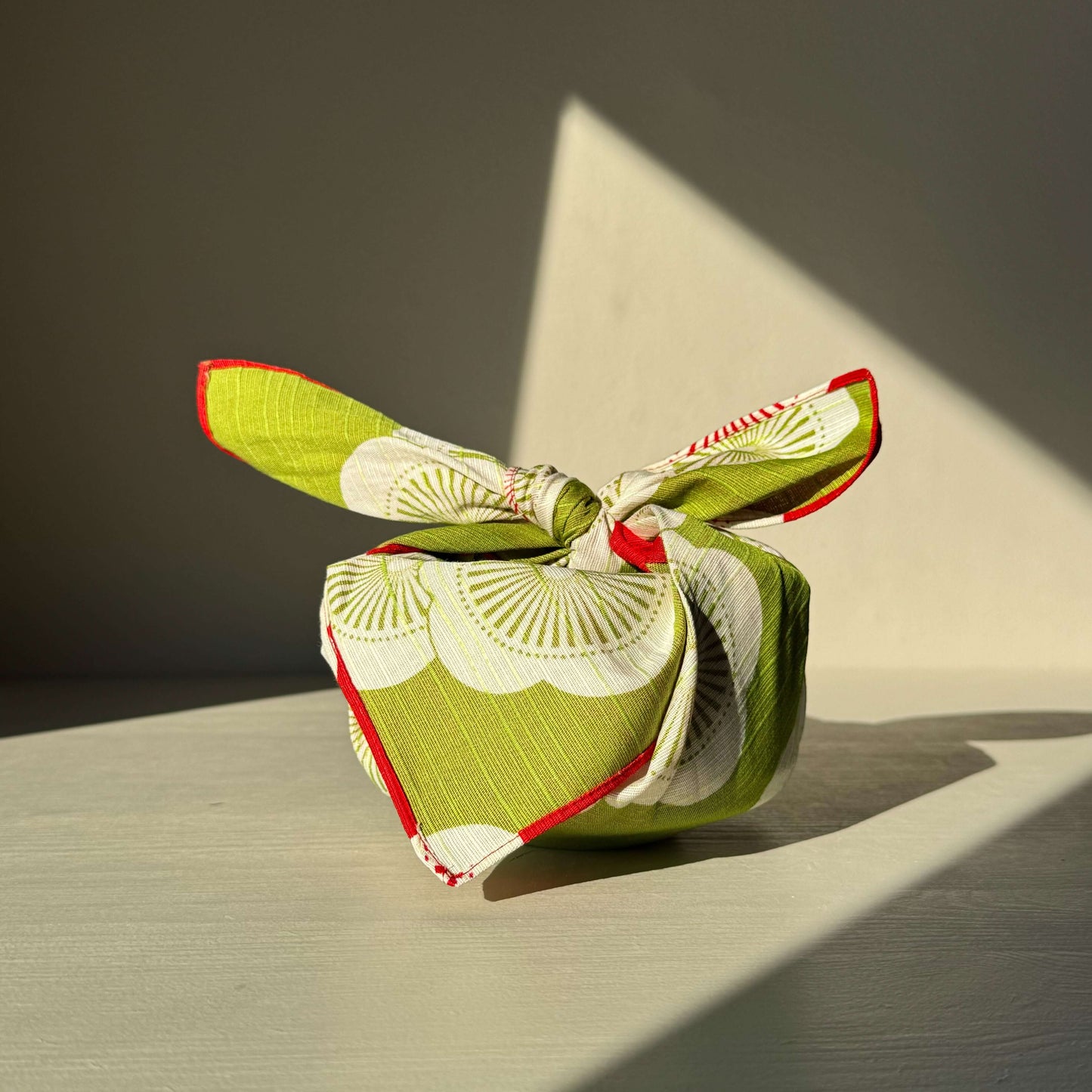 Small Furoshiki in red and green with plum blossom pattern, symbolizing happiness and resilience; eco-friendly and reusable wrap.
