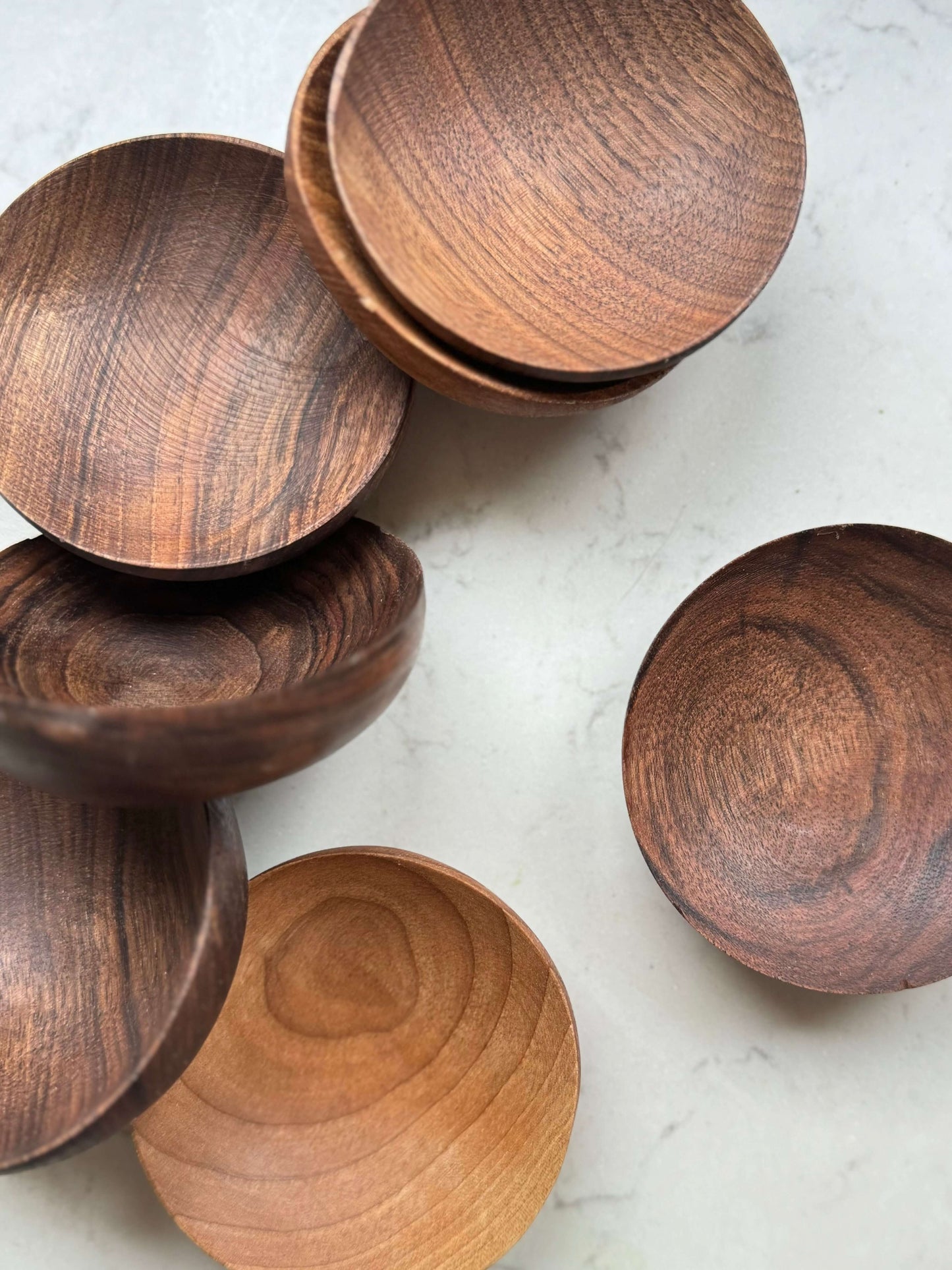 Hand-carved walnut wood bowls with unique grain patterns, perfect for serving tea moments. Crafted in Marrakech.