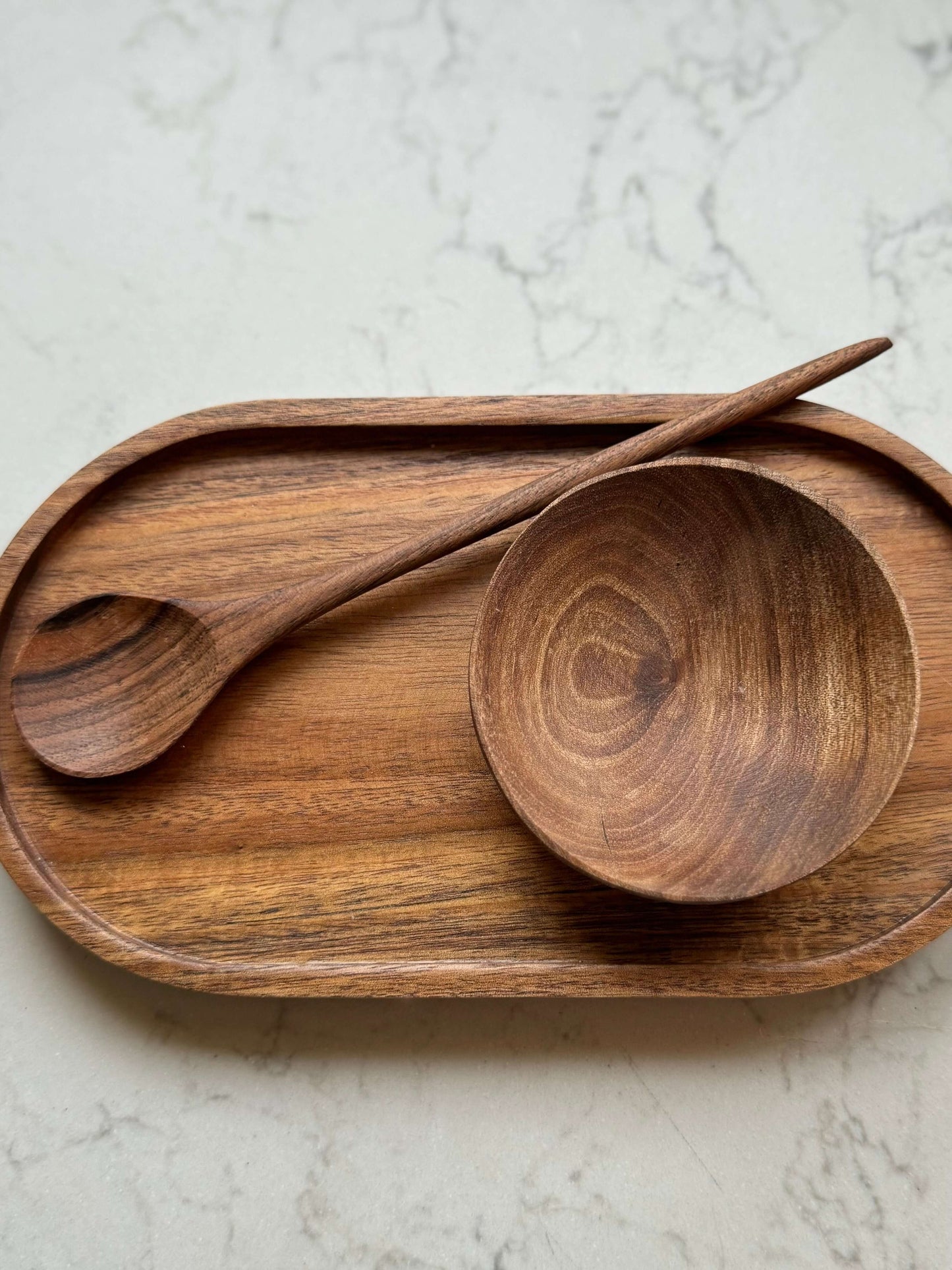 Small hand-carved walnut wood bowl and spoon on wooden tray, showcasing rich grain and unique character.