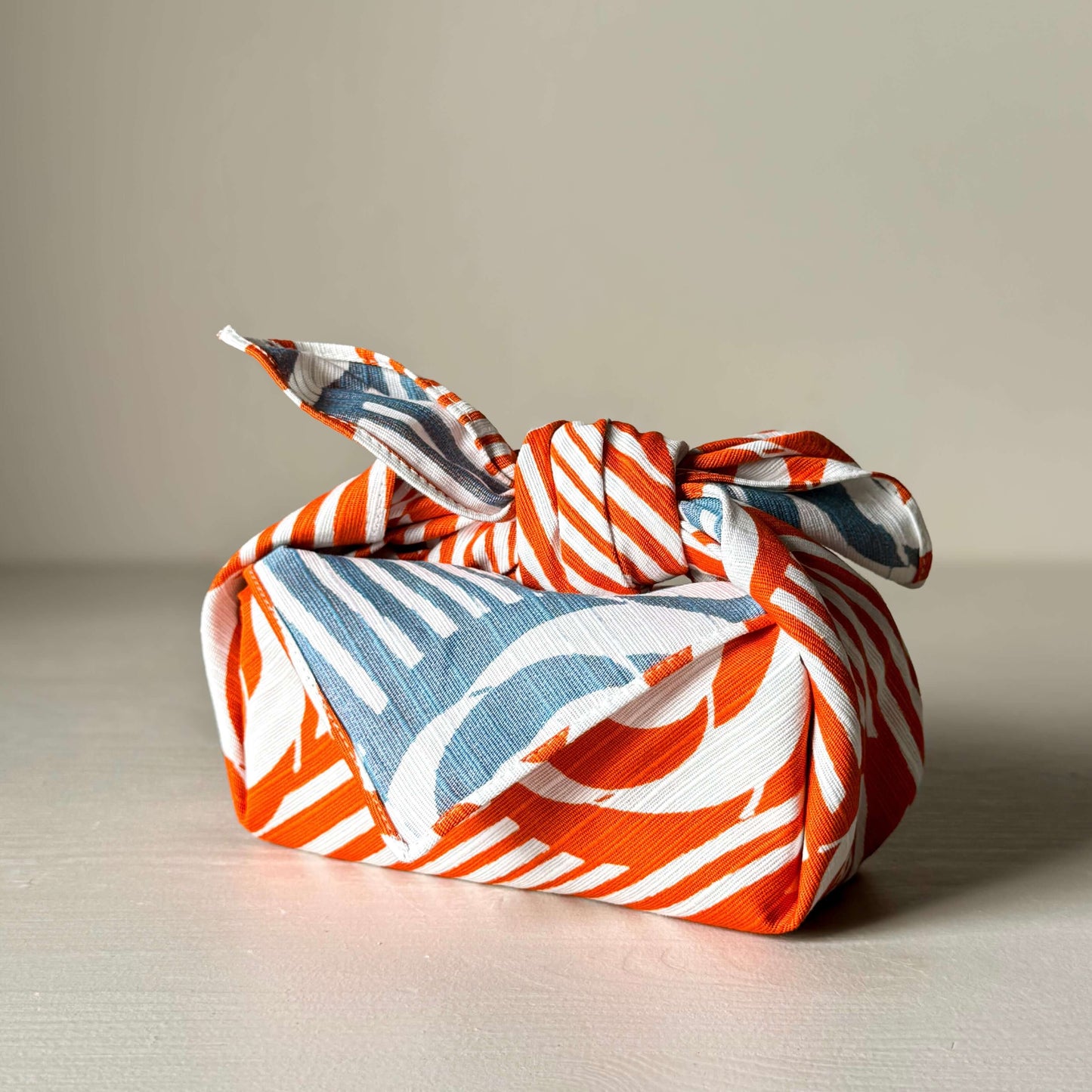 Small Furoshiki with Camellia print in orange and blue, folded elegantly, showcasing traditional Japanese floral pattern, 48cm x 48cm.