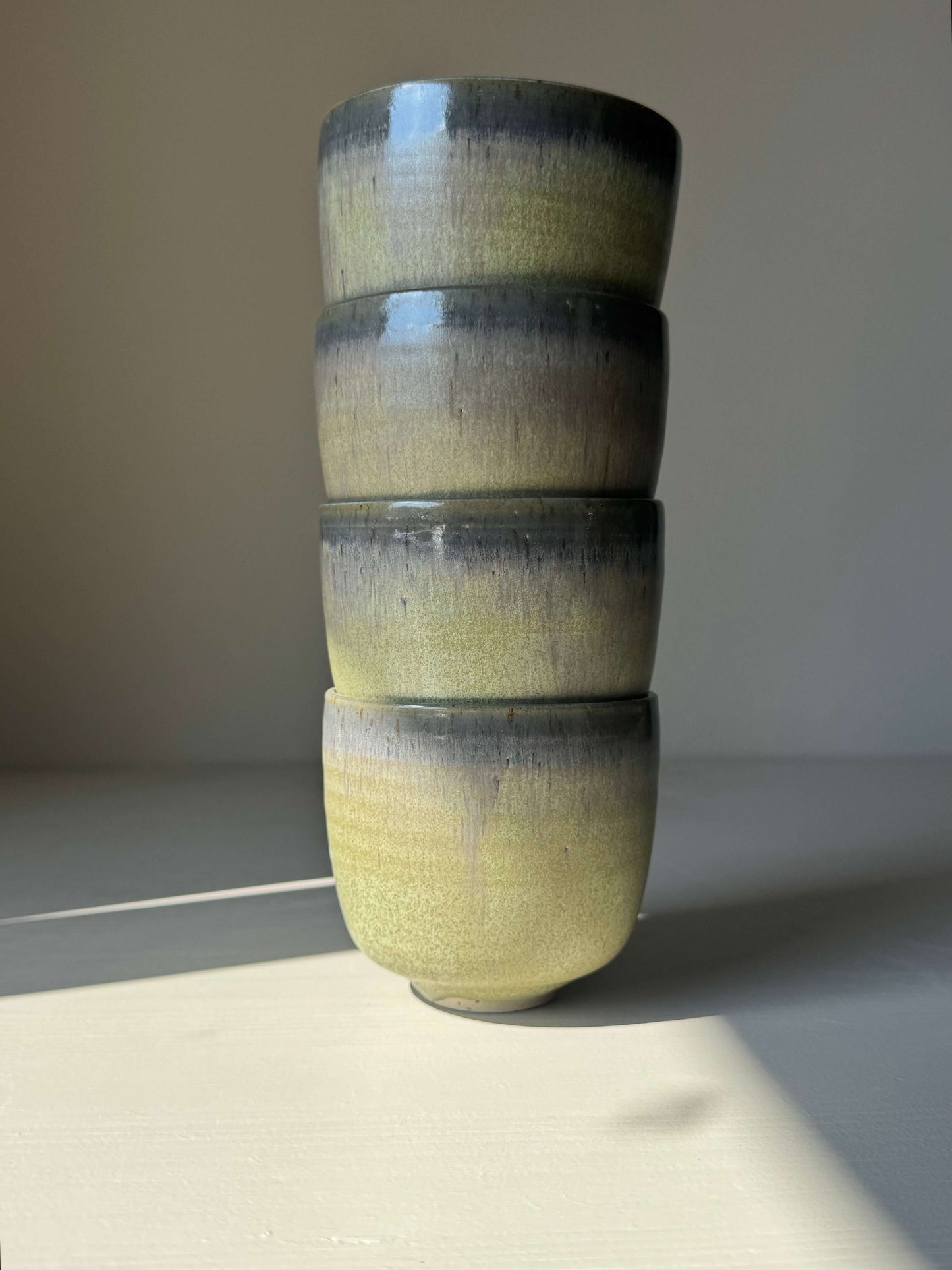 Stack of handmade ceramic Cups - Satin Blue with misty grey to olive green gradient glaze, showcasing rounded design.