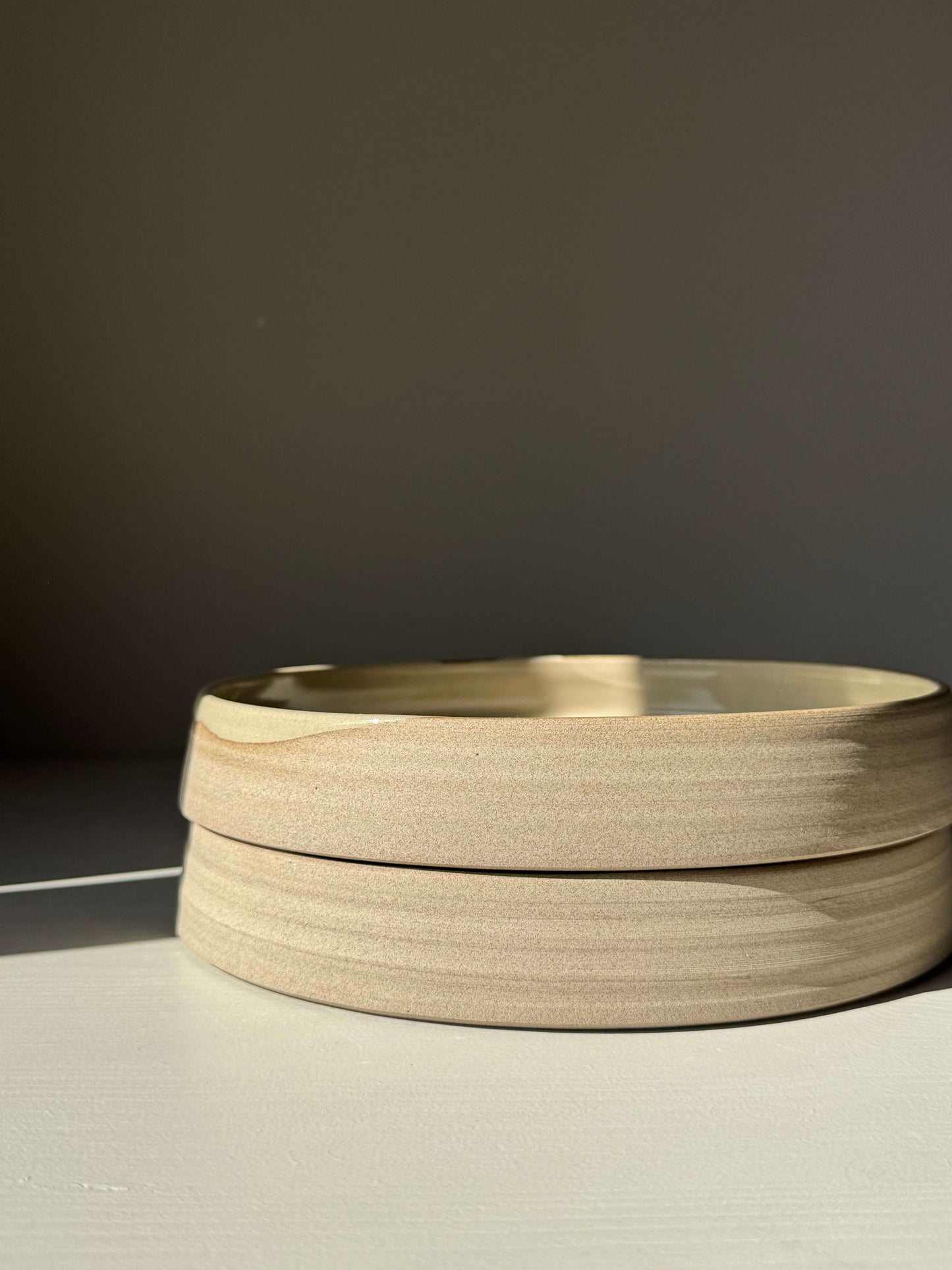 Stack of unfinished round wooden bowls on a light surface.