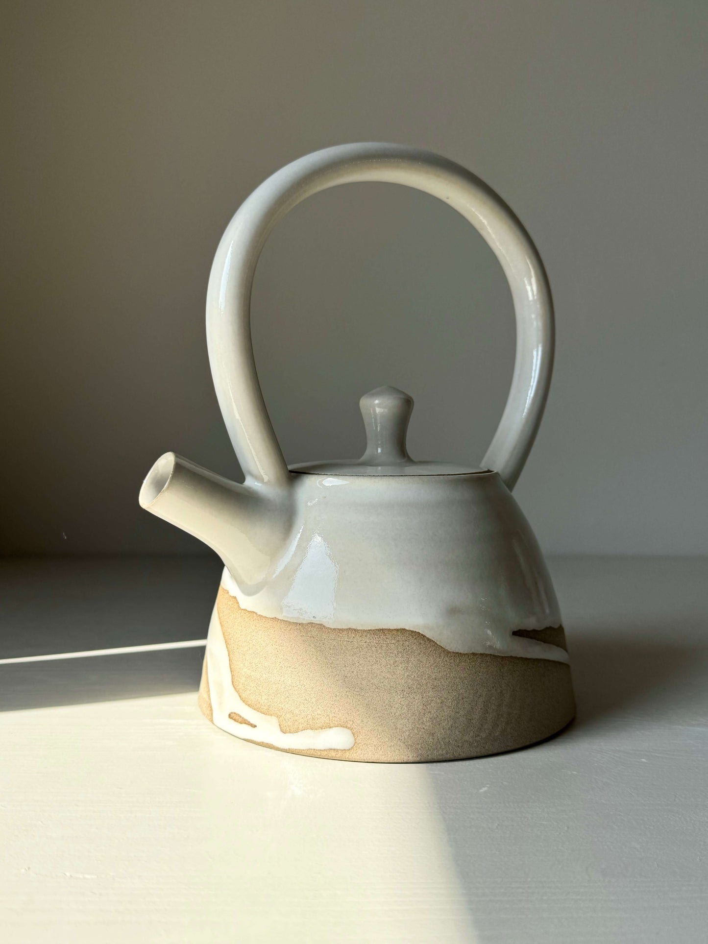 Yuki Series #03 teapot with tall looped handle and white glaze, featuring raw clay base for a serene, balanced design.