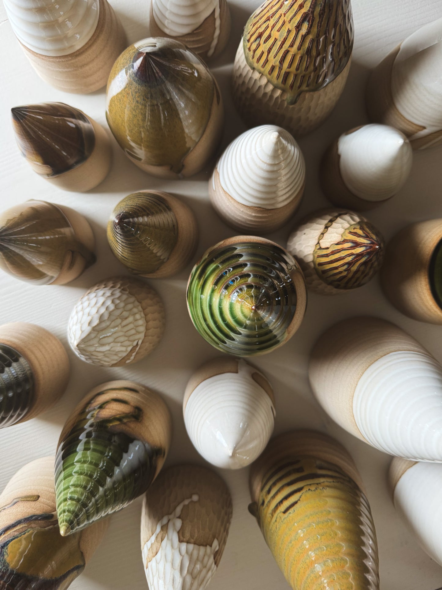 Assorted ceramic art pieces with various textures and colors, arranged in a circular pattern on a light background.