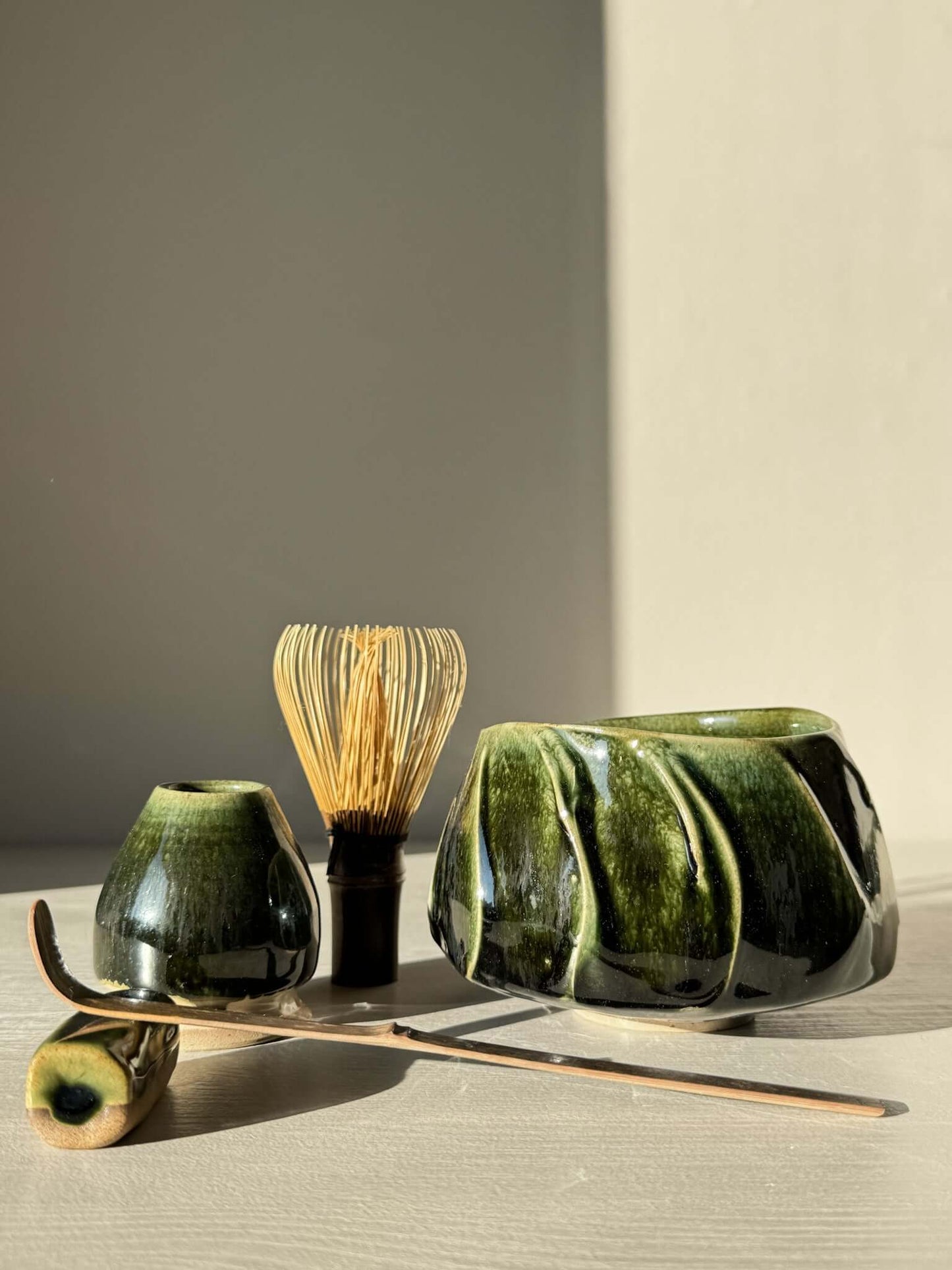 Textured Matcha Bowl - Hinoki #14 with green glaze and bamboo whisk, showcasing natural beauty and craftsmanship in a serene setting.