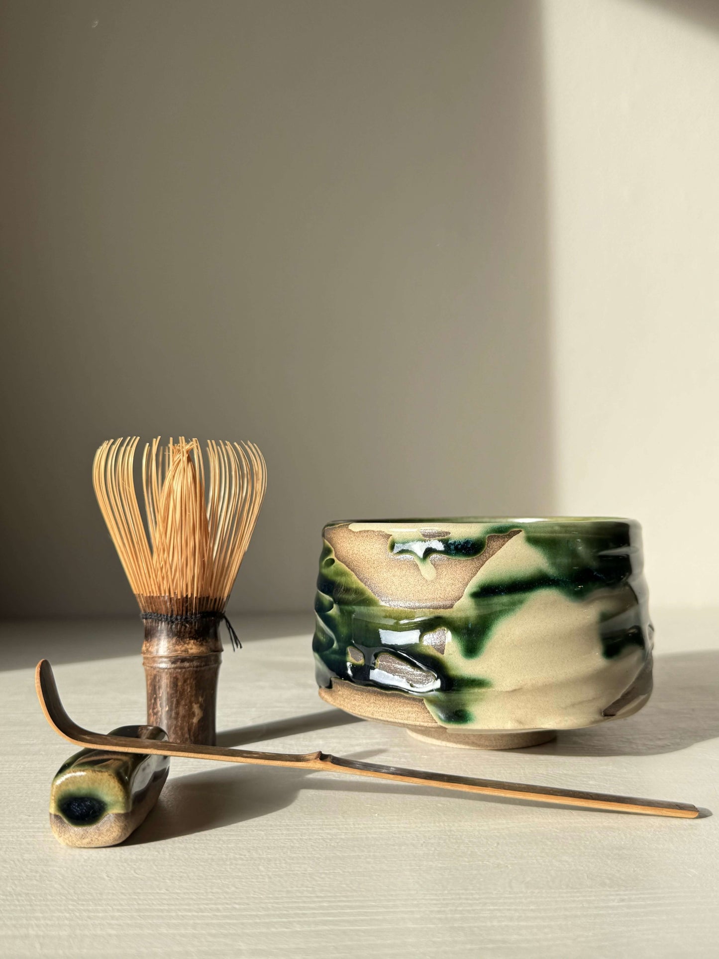 Textured Matcha Bowl – Mori #02, handmade ceramic with forest-green glaze, alongside traditional bamboo matcha whisk and scoop.