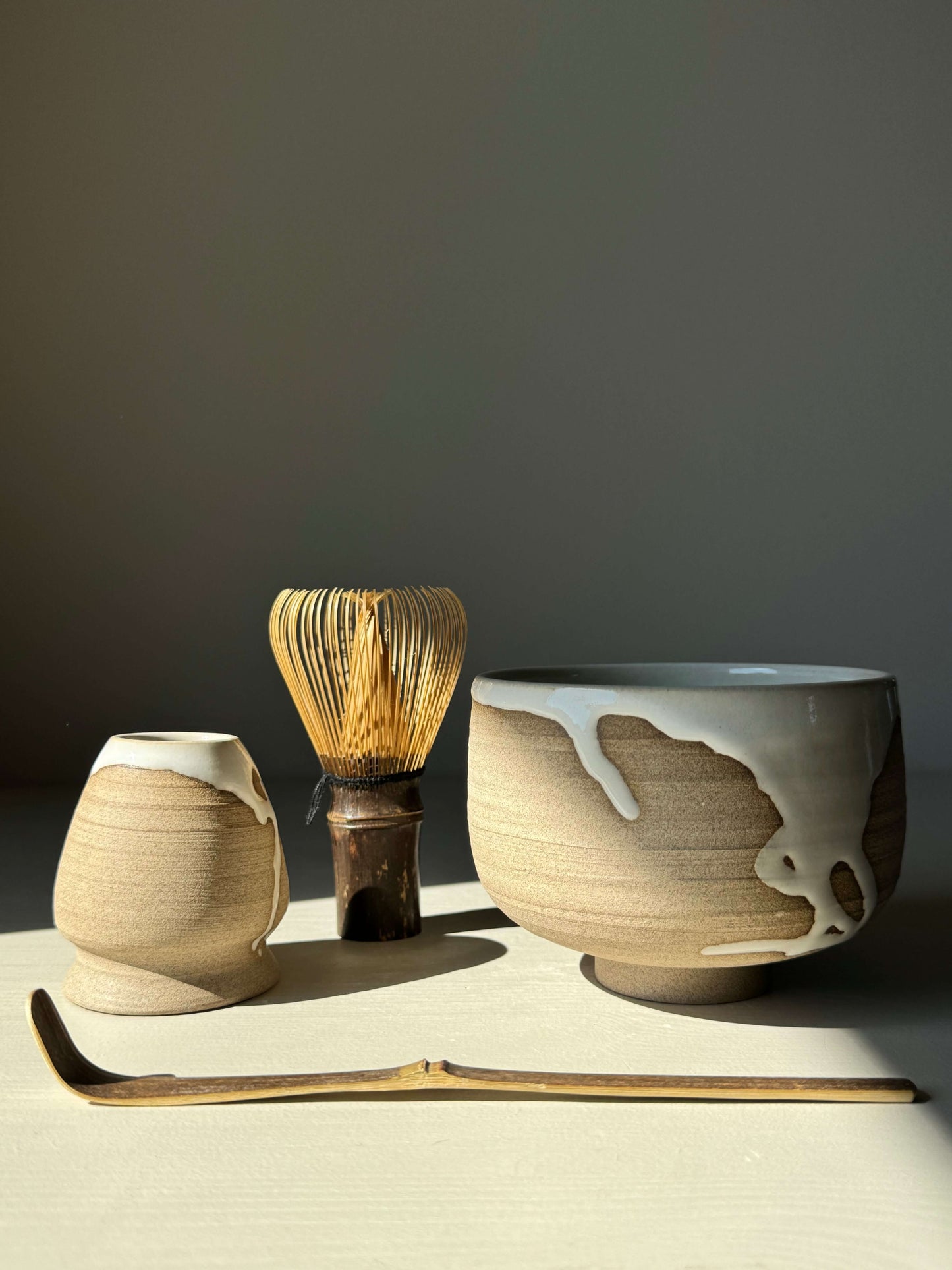 Handmade Yuki Series Matcha Bowl with whisk and scoop on a table, featuring toffee clay and glossy white glaze.