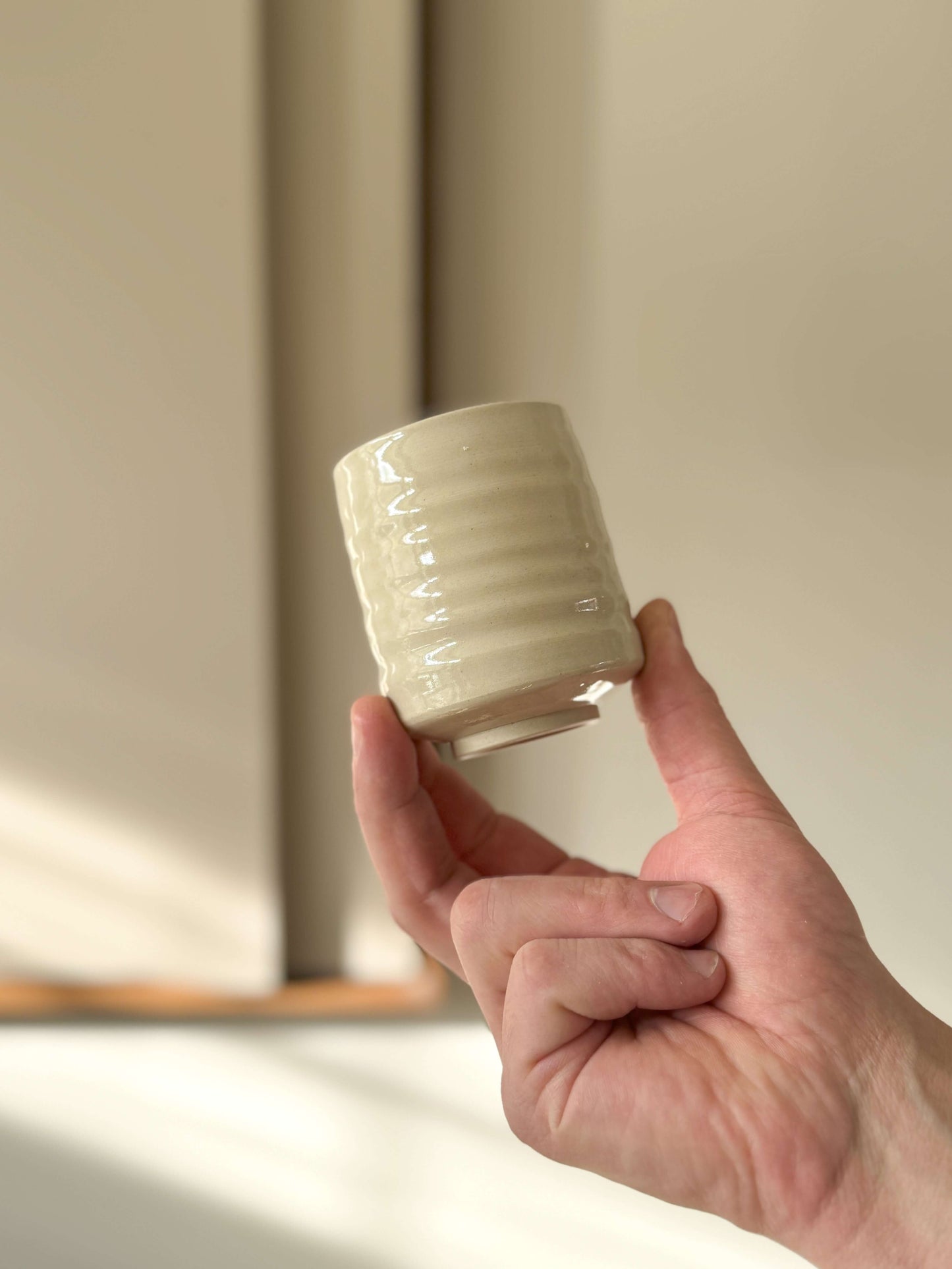 Person holding a wheel-thrown Yunomi cup with clear glaze, showcasing the compact design in high-fired stoneware clay.