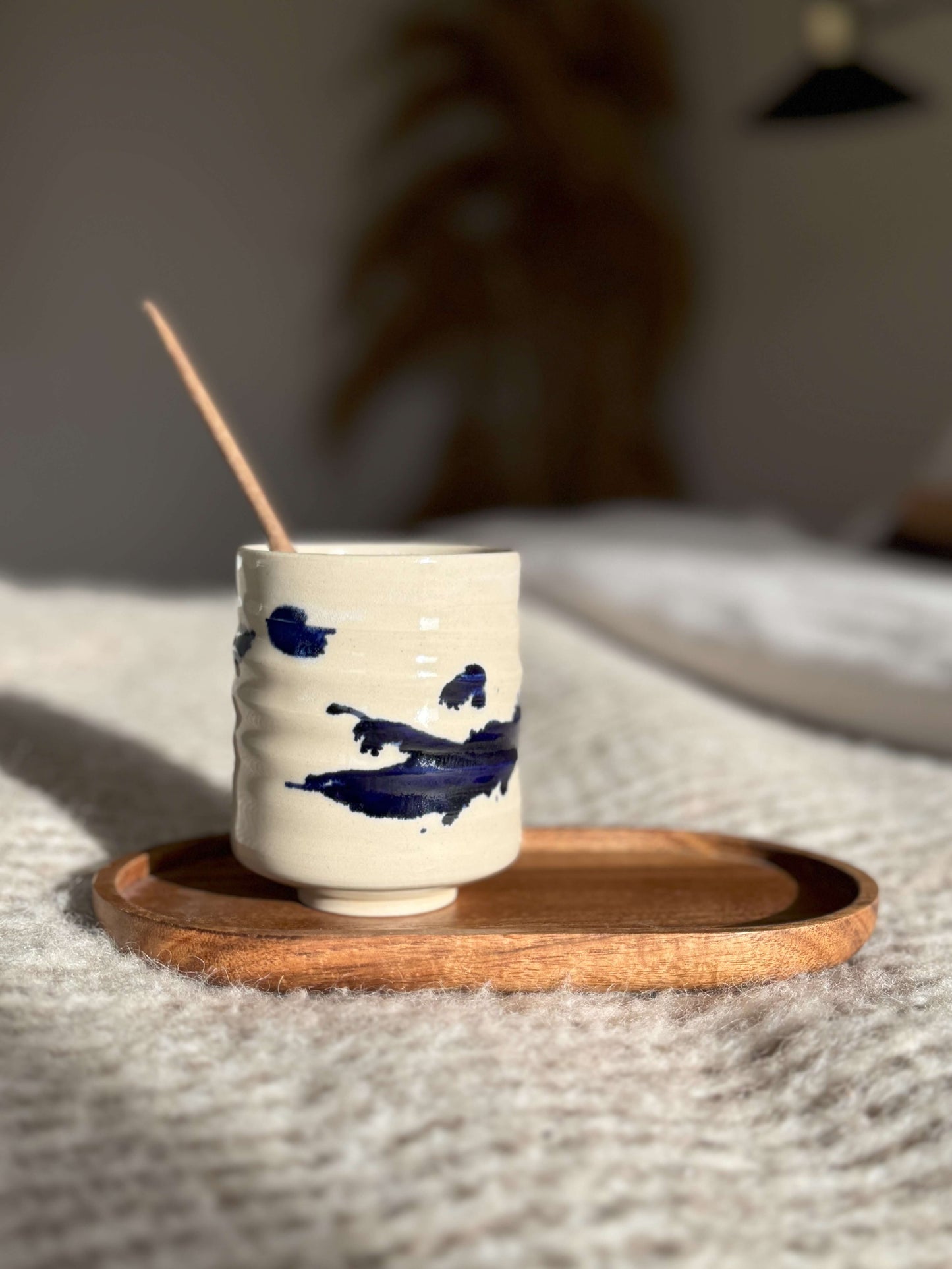 Handmade ceramic Yunomi Cup - Gosu Series with cobalt blue splashes on a wooden tray.