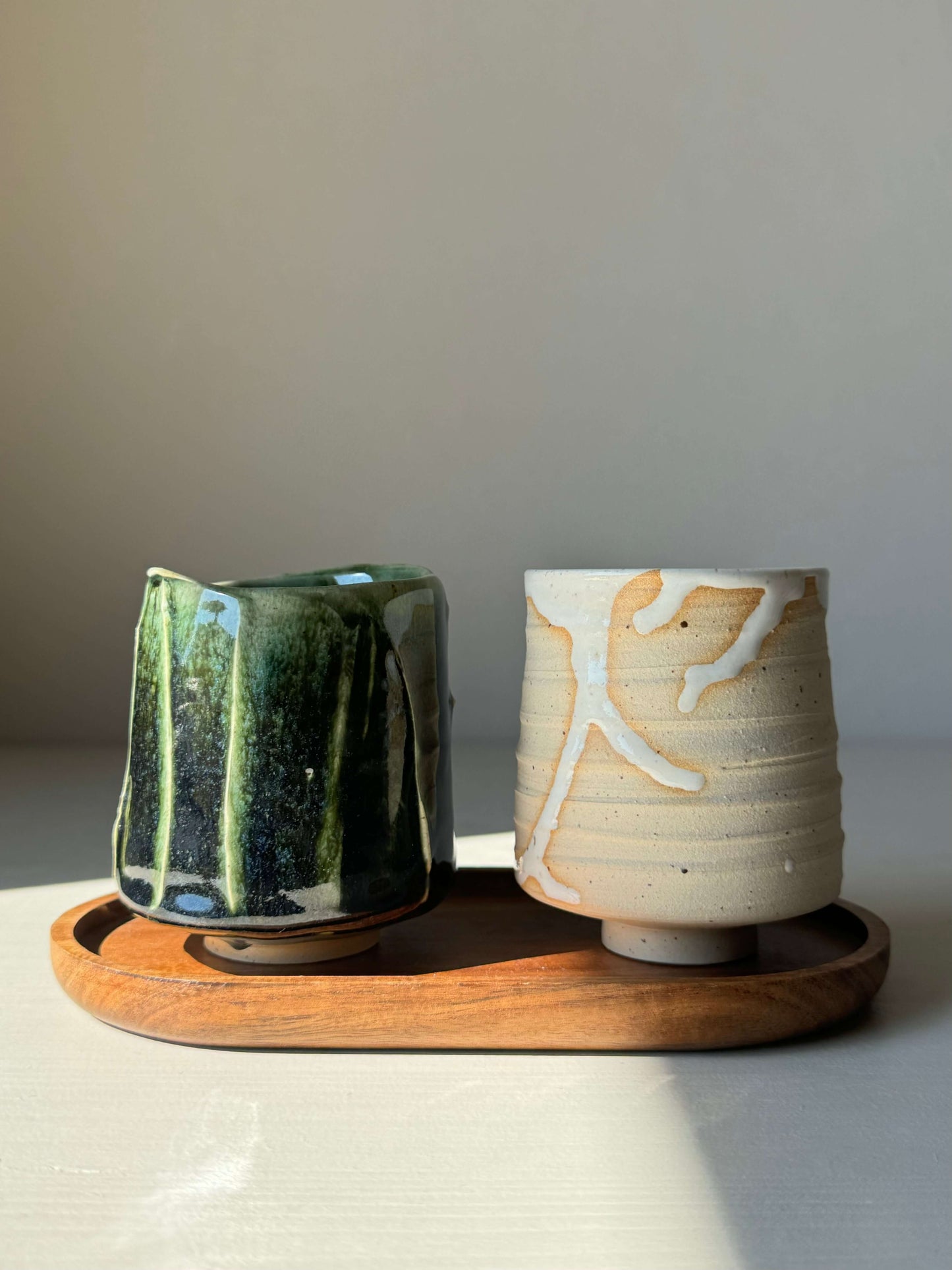 Set of Yunomi Cups from Yuki & Hinoki Series, featuring snow-like and forest green designs, on a wooden tray.