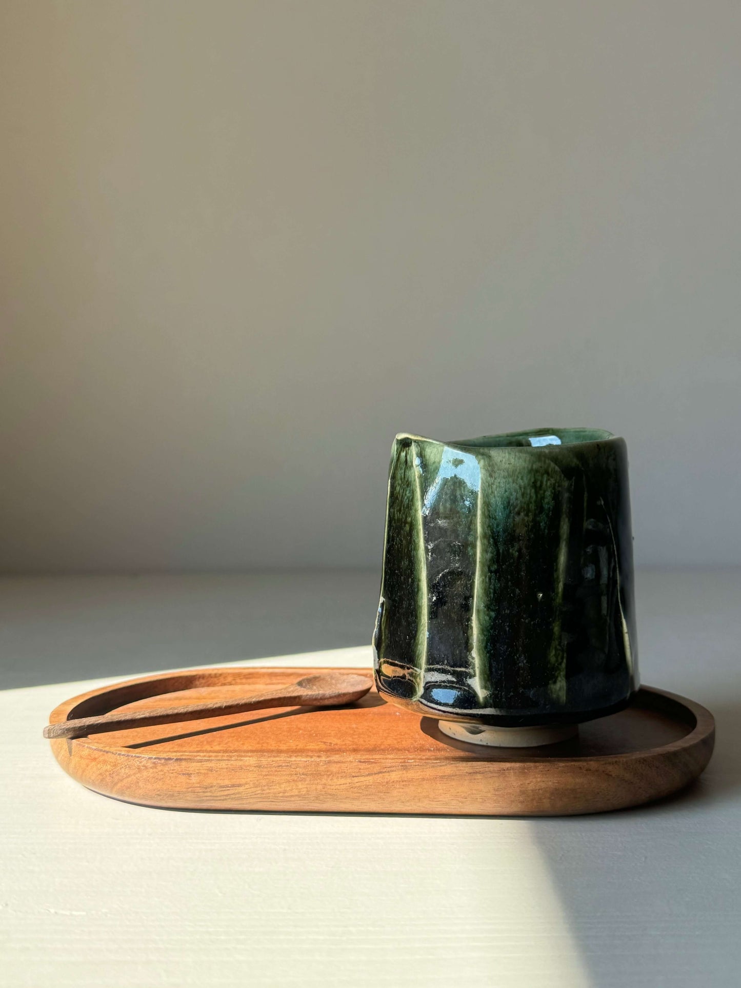 Yunomi Hinoki series cup in deep forest green on wooden tray, highlighting its elegant design and high-fired stoneware finish.