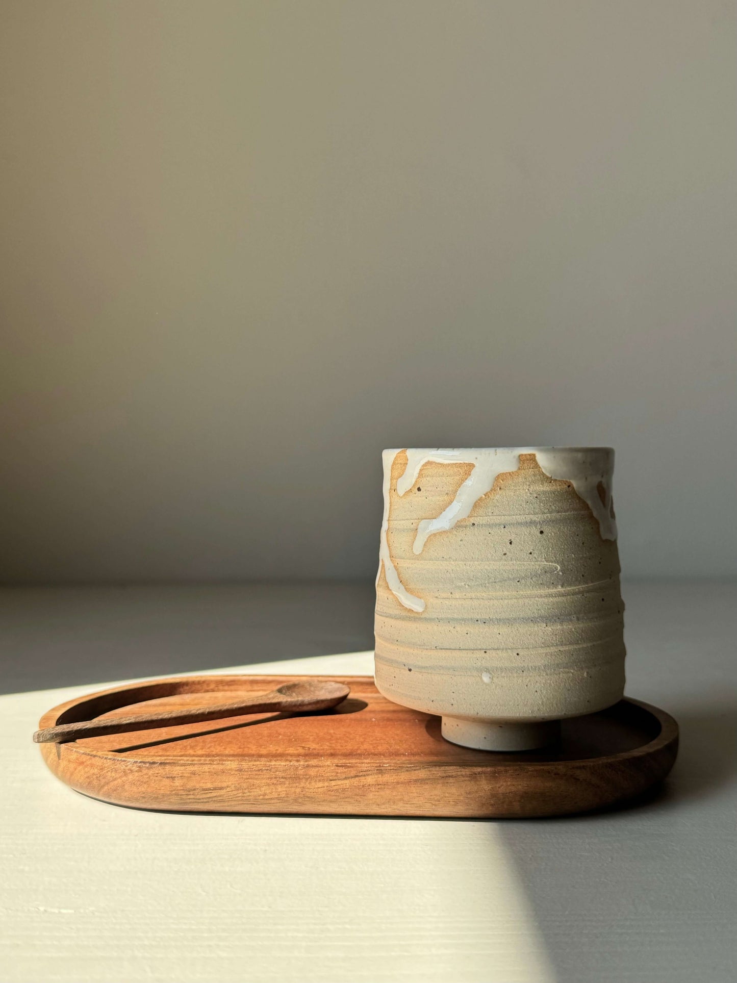 Yunomi cup from Yuki & Hinoki Series on a wooden tray with spoon, showcasing natural high-fired stoneware design and snow tones.