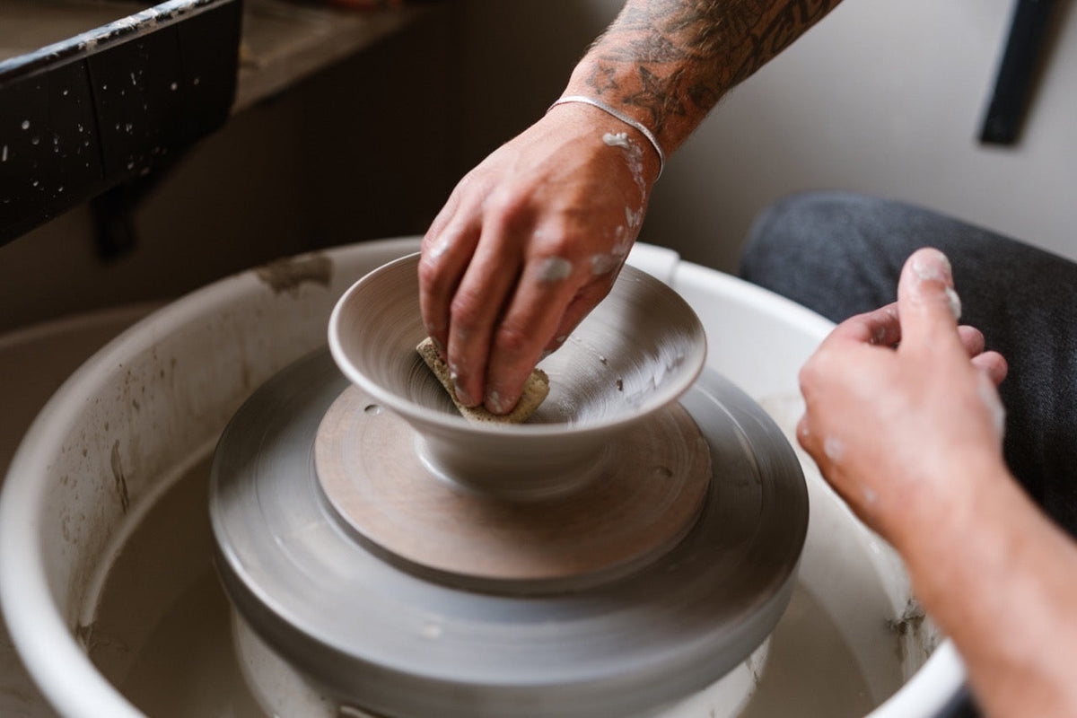 Hands shaping a ceramic bowl on a pottery wheel — part of the process of starting a pottery business