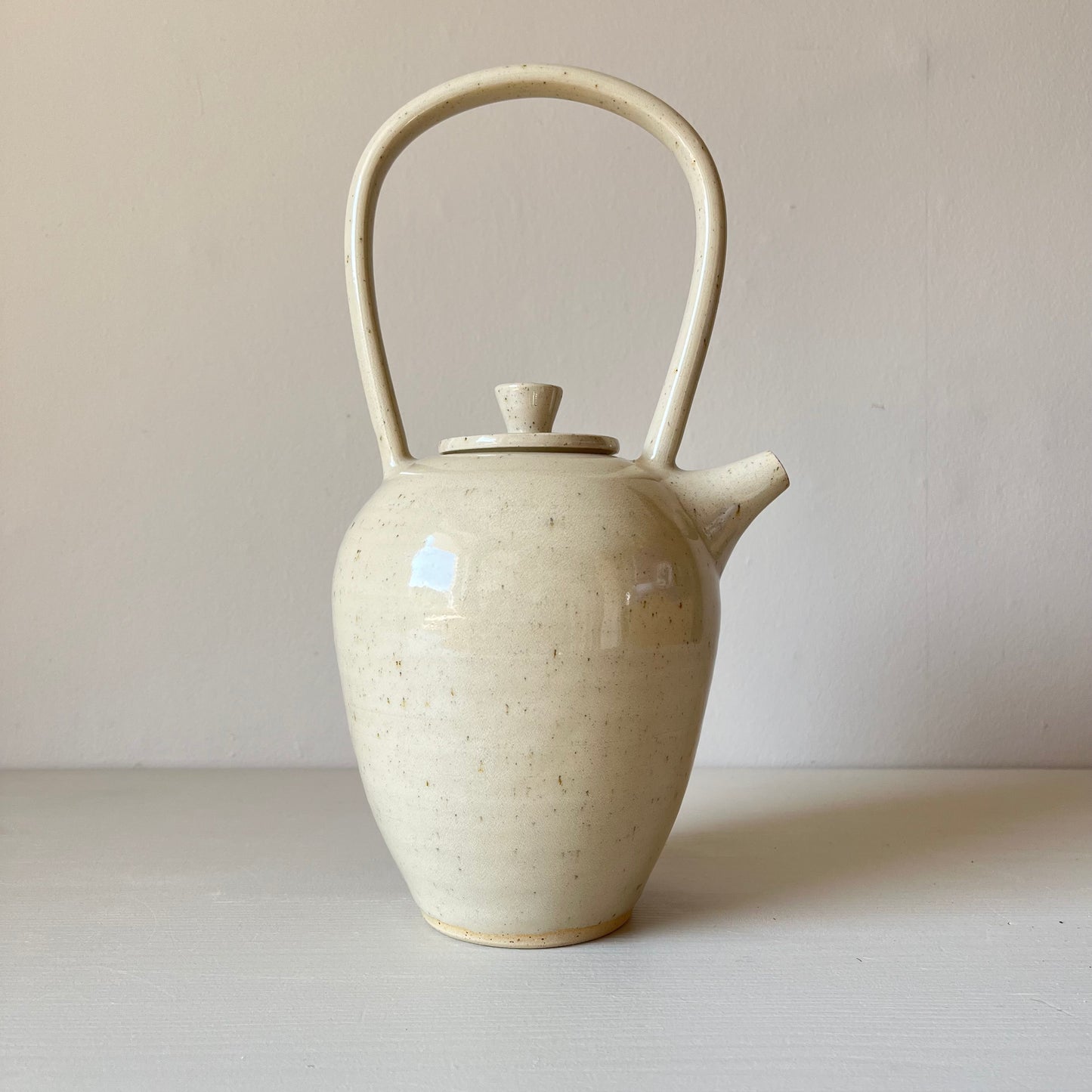 a large cream handmade stoneware teapot on a neutral background