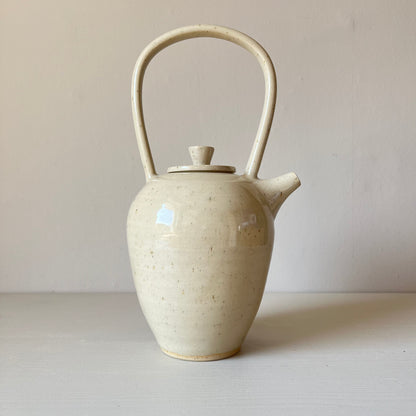 a large cream handmade stoneware teapot on a neutral background