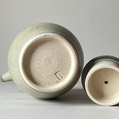 bottom view of a blue ceramic teapot on a neutral background