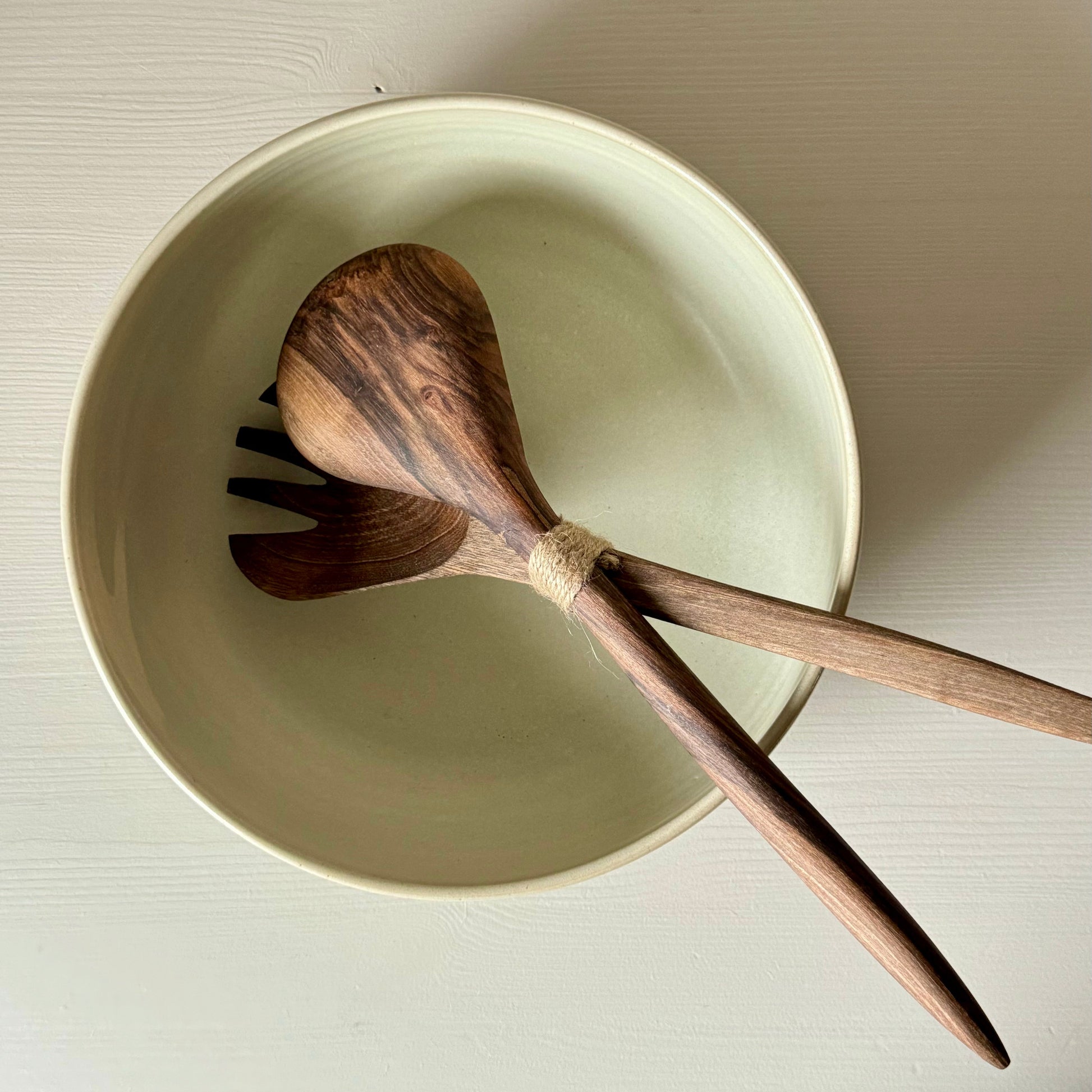 Large wooden salad serving spoons witha a handmade ceramic dish