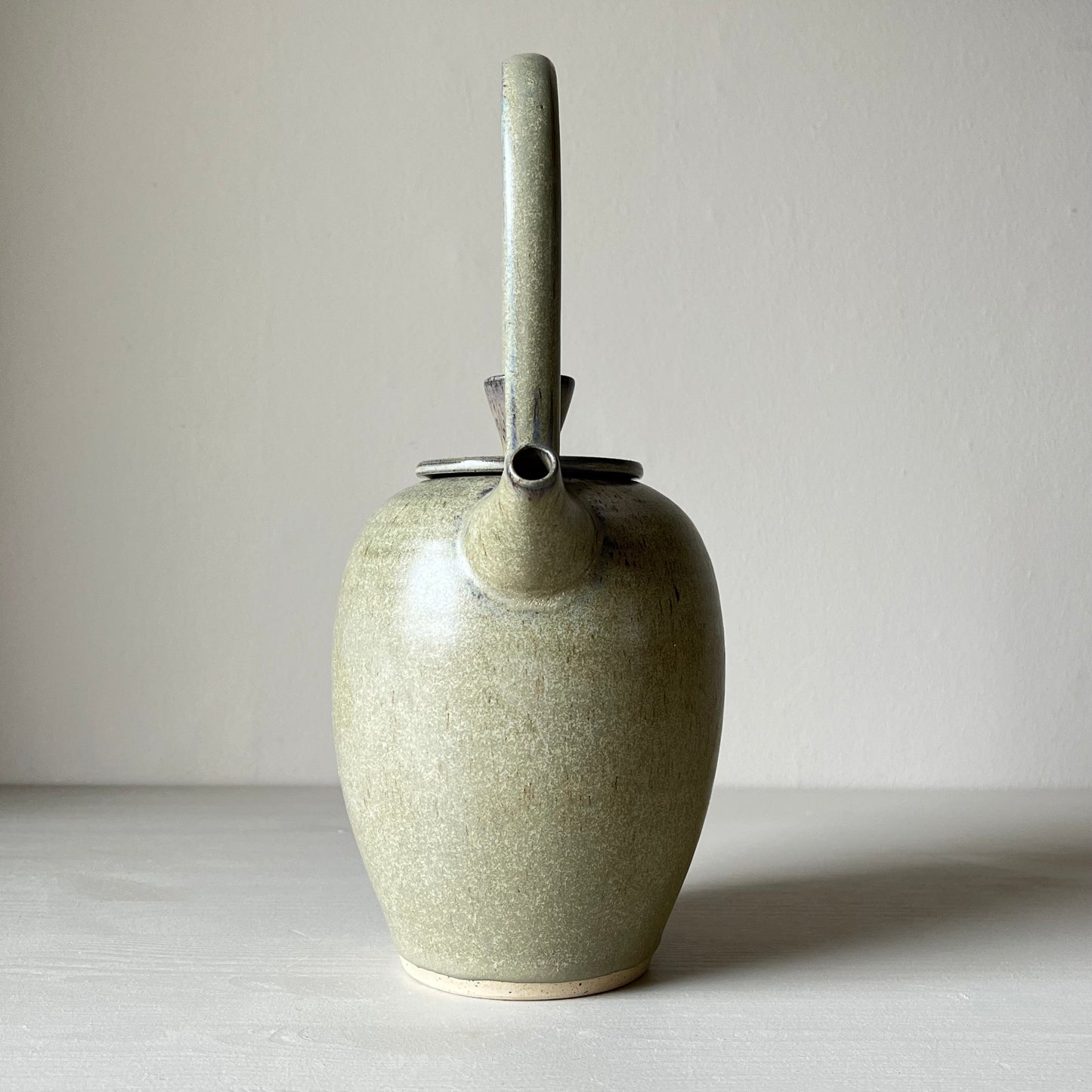 a front view of a blue ceramic teapot on a neutral background