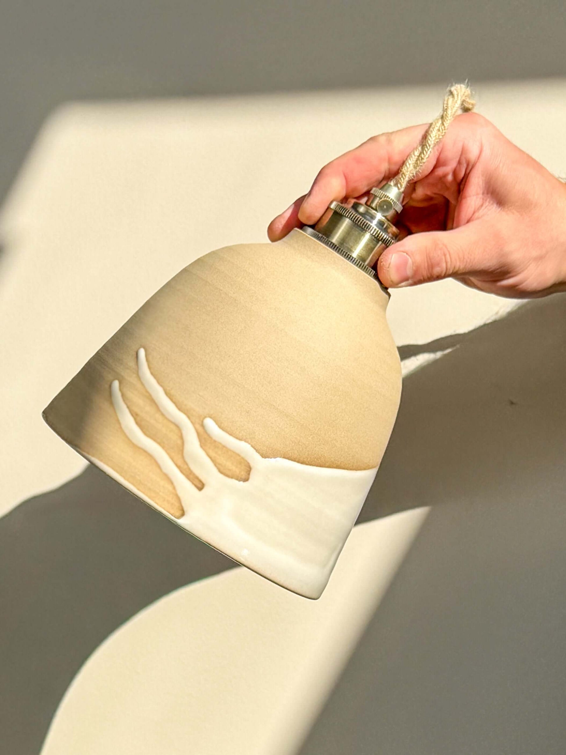 Ceramic Lamp Shade – Yuki #04 with glossy white glaze and raw clay exterior being held to showcase design.