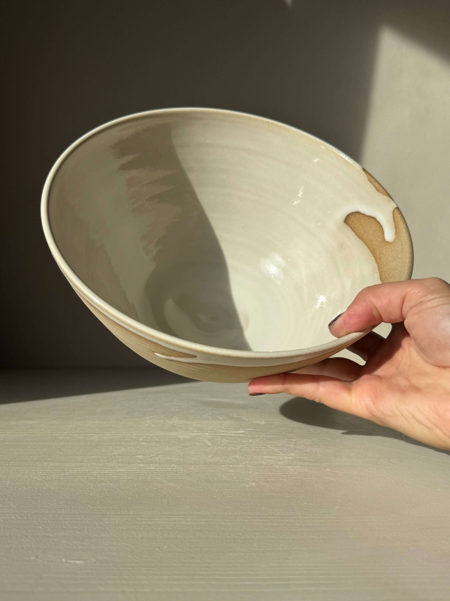 Hand holding handmade ceramic Medium Bowl - Yuki #02 with glossy white glaze and toffee-colored clay.