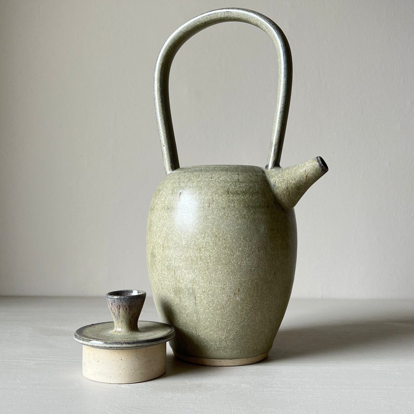 A blue ceramic teapot and lid on a neutral background