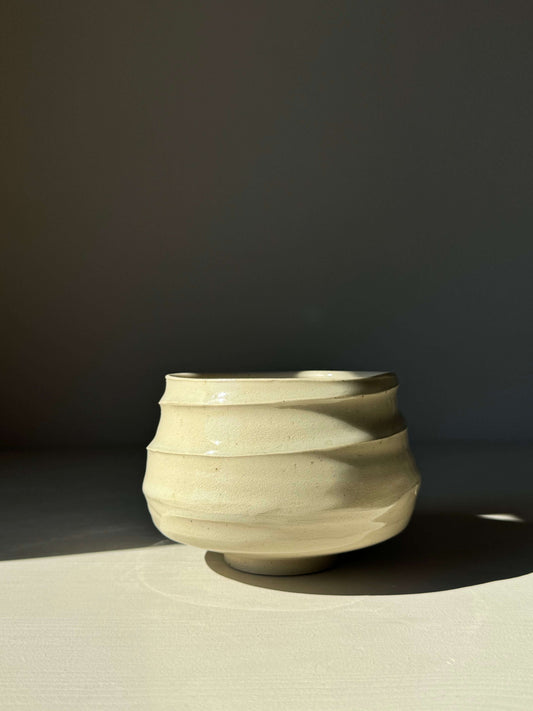 Textured rounded matcha bowl with clear glaze, showcasing subtle clay textures and earthy tones in natural light.