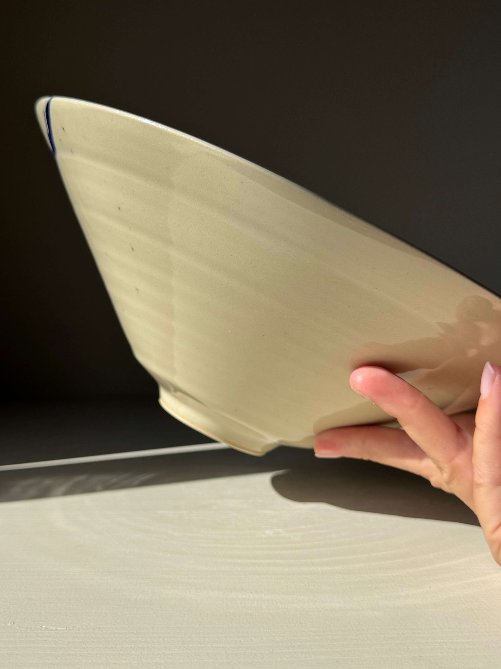 Handmade ceramic Medium Bowl - Gosu Series #01 with bold cobalt splashes, held gently, showcasing its soft, natural form.