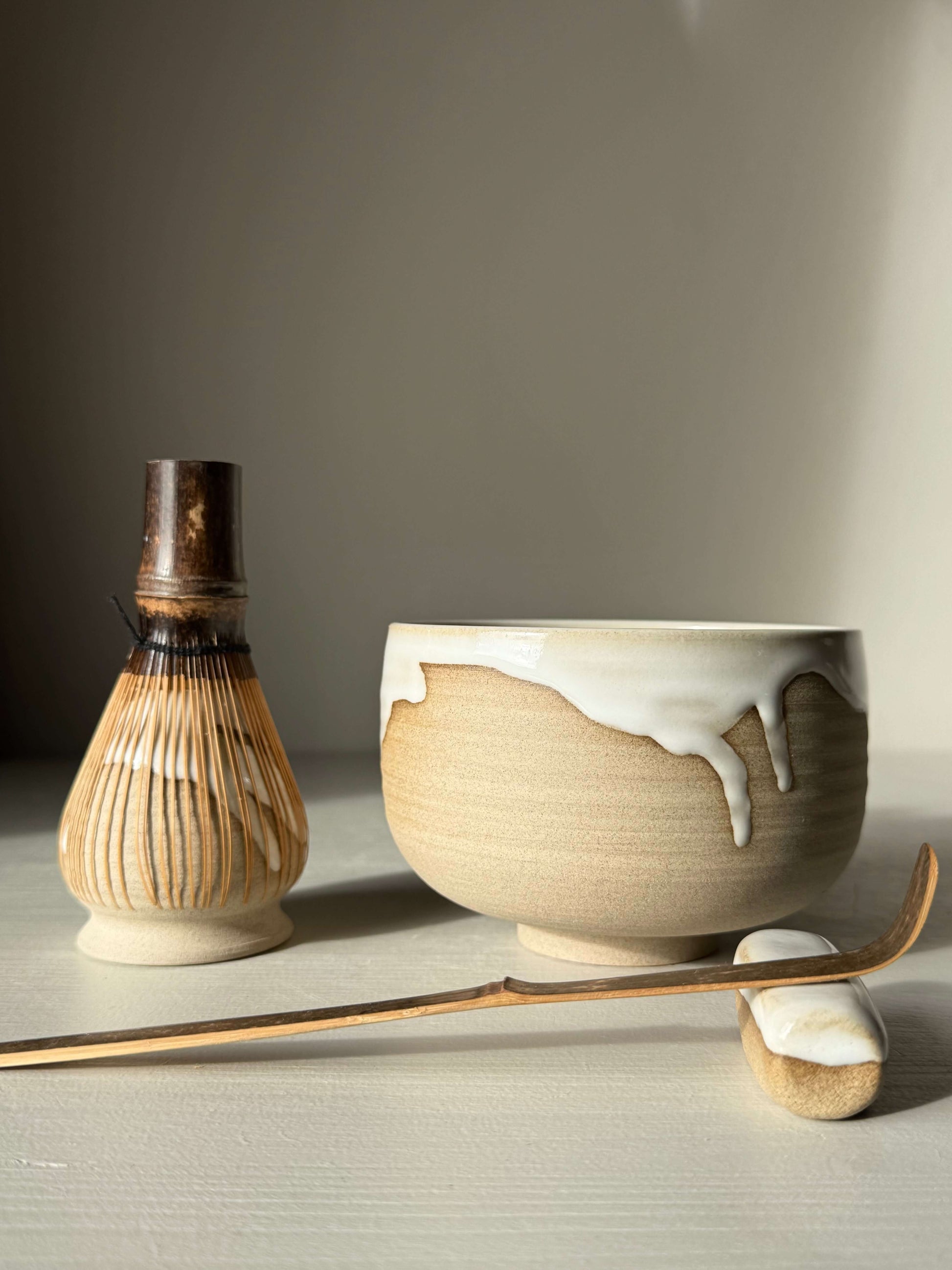 Matcha Bowl – Yuki #01, handmade ceramic bowl with glossy white glaze and toffee clay, shown with traditional matcha whisk and scoop.