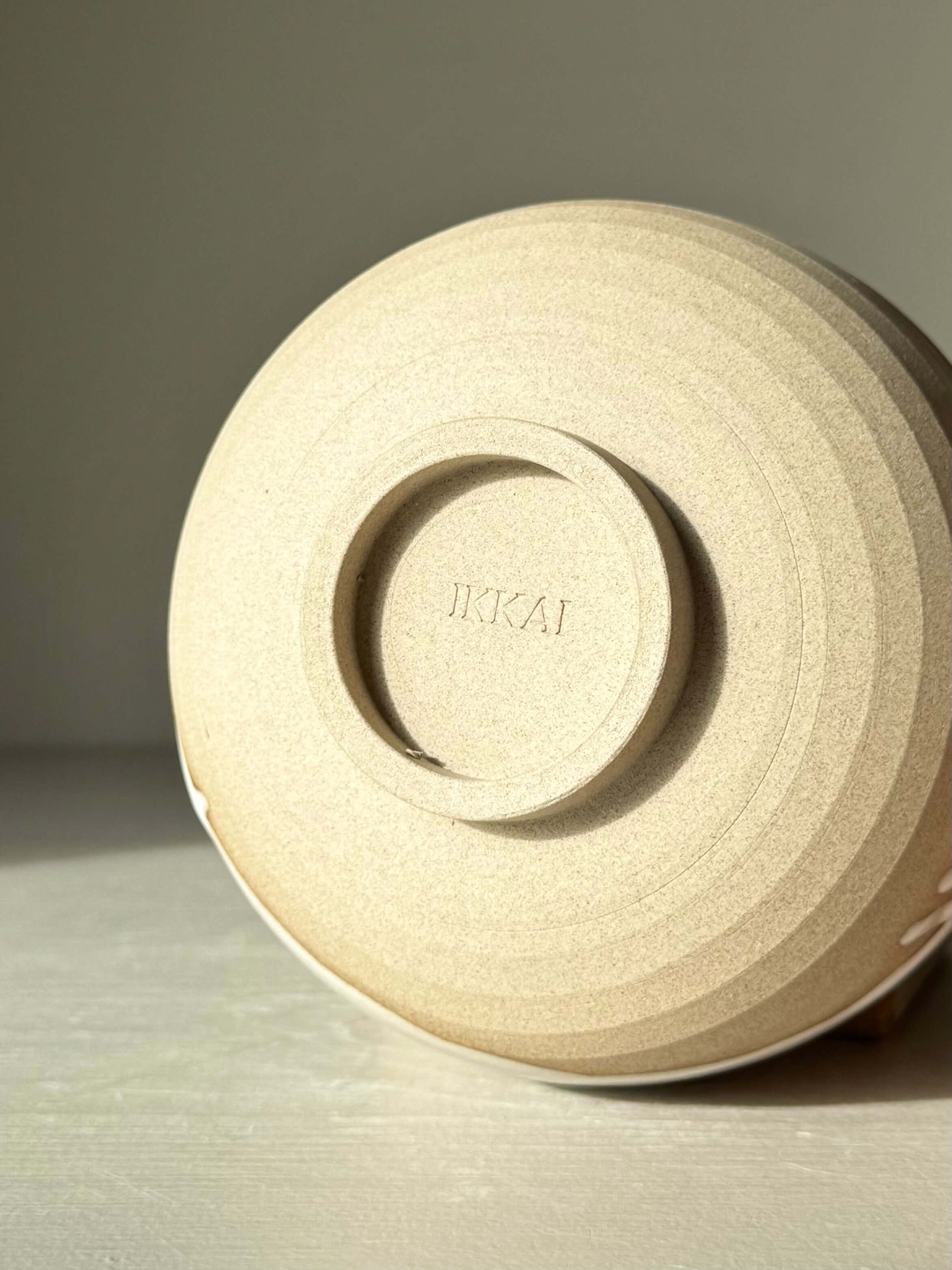 Base of handmade ceramic Matcha Bowl – Yuki #03 showcasing textured toffee clay finish with a stamped design.