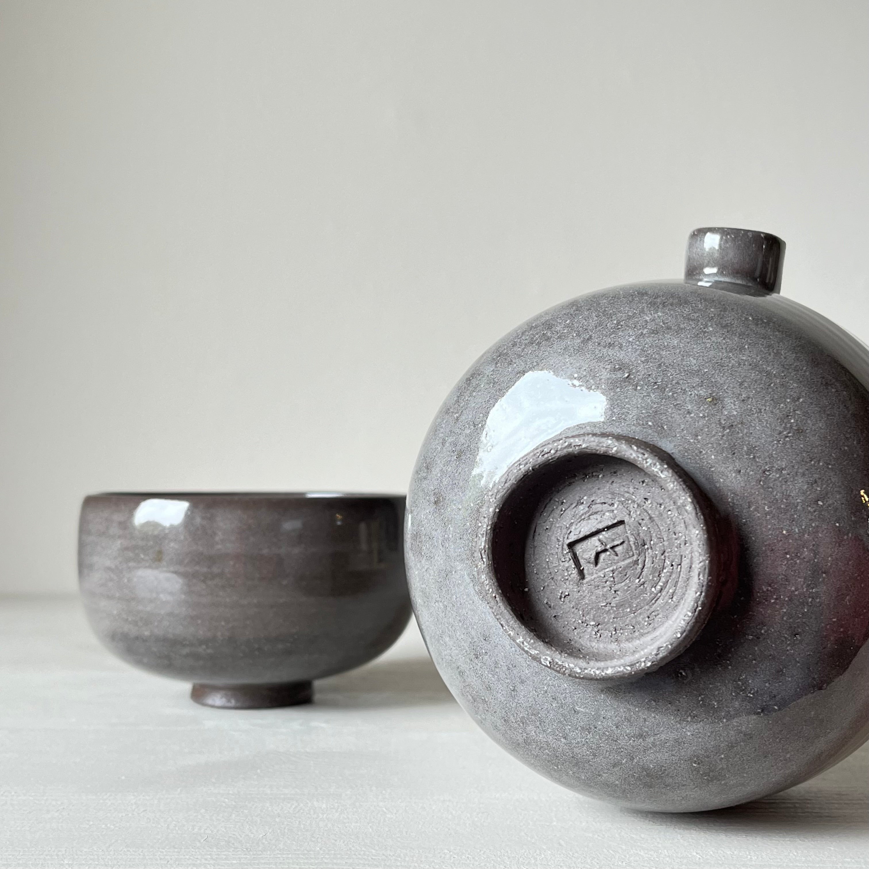 a view of the foot of a gray ceramic matcha bowl laying on its side and in the background another matching gray ceramic matcha bowl