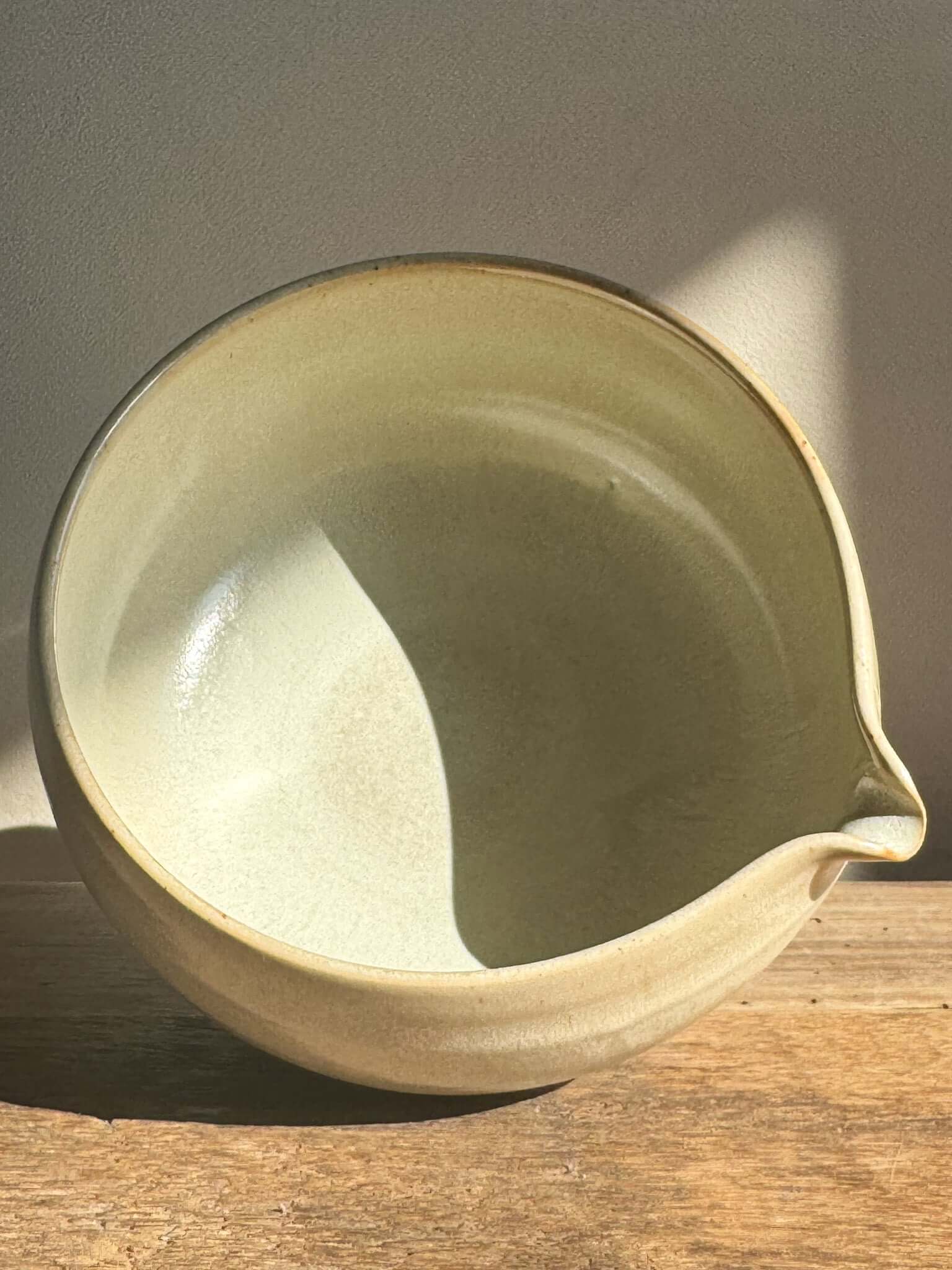Katakuchi matcha bowl with spout in Moonstone glaze on wooden surface, showcasing soft rounded design and natural hues.