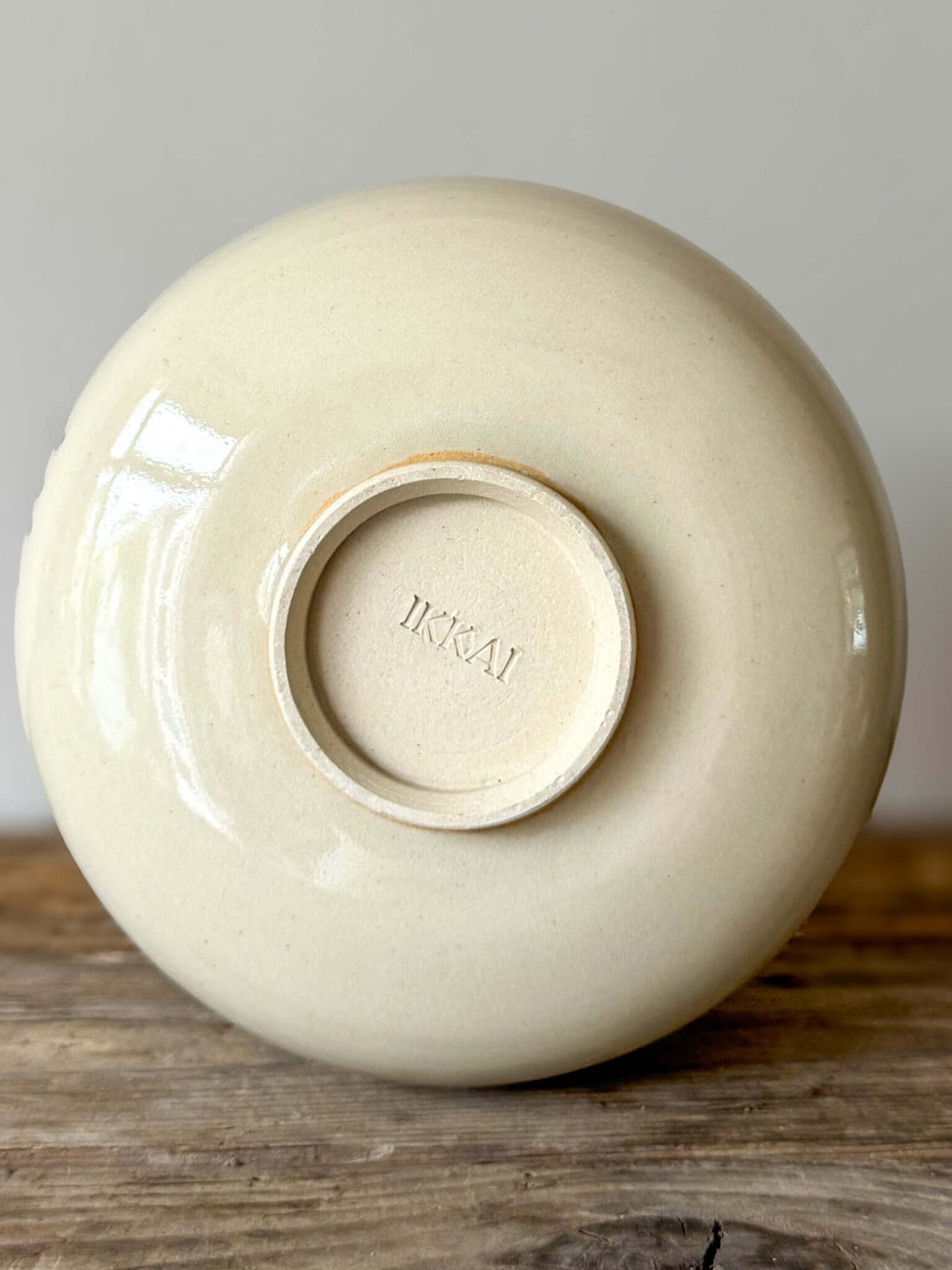 Underside of Large Rounded Matcha Bowl from Gosu Series showing artist's mark, placed on a wooden surface. Elegant ceramic design.