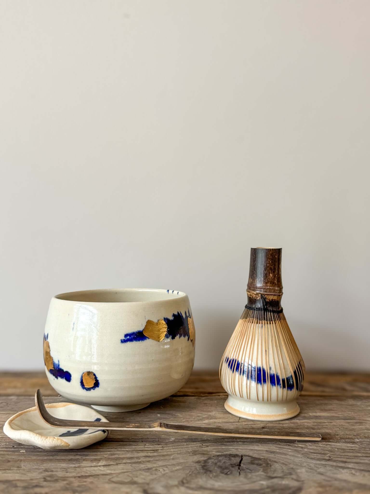 Rounded Matcha Bowl with cobalt glaze and gold leaf design, part of the Gosu Series, on a wooden surface with tea tools.