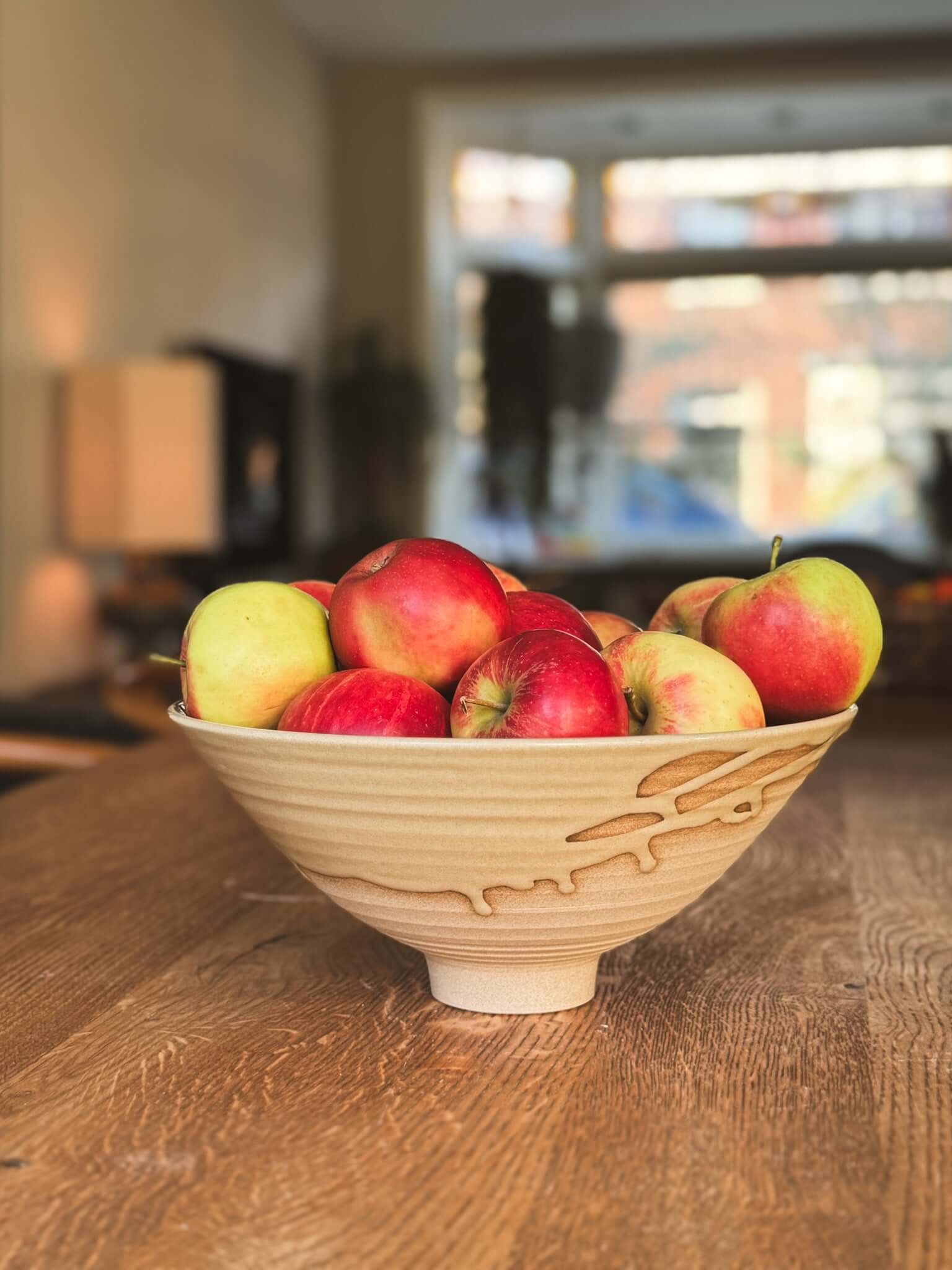 Medium Bowl - Inyo #01 filled with colorful apples on a wooden table, showcasing its sculptural design and textured exterior.