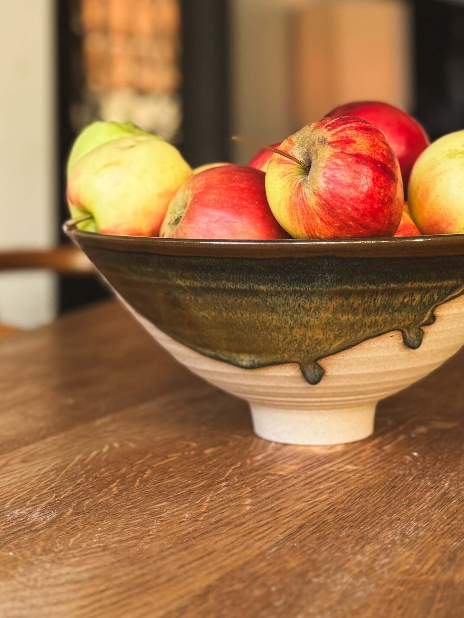 Medium Bowl - Inyo #01 with apples on wooden table, showcasing its sculptural design, golden tones, and carved exterior.