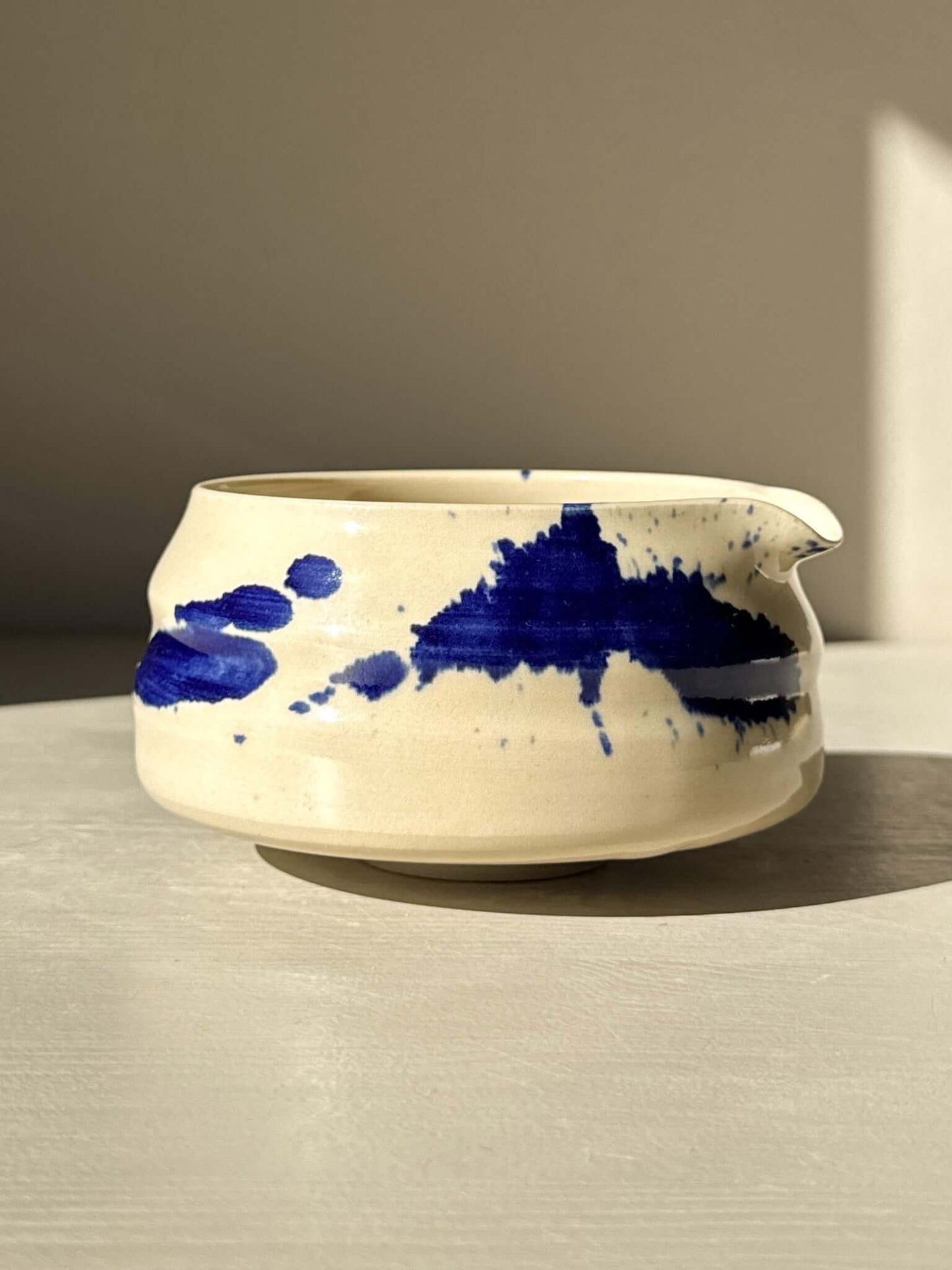 Matcha Bowl with Spout – Gosu #02, shallow round design with a soft spout for easy pouring, in a light ceramic finish with blue designs.