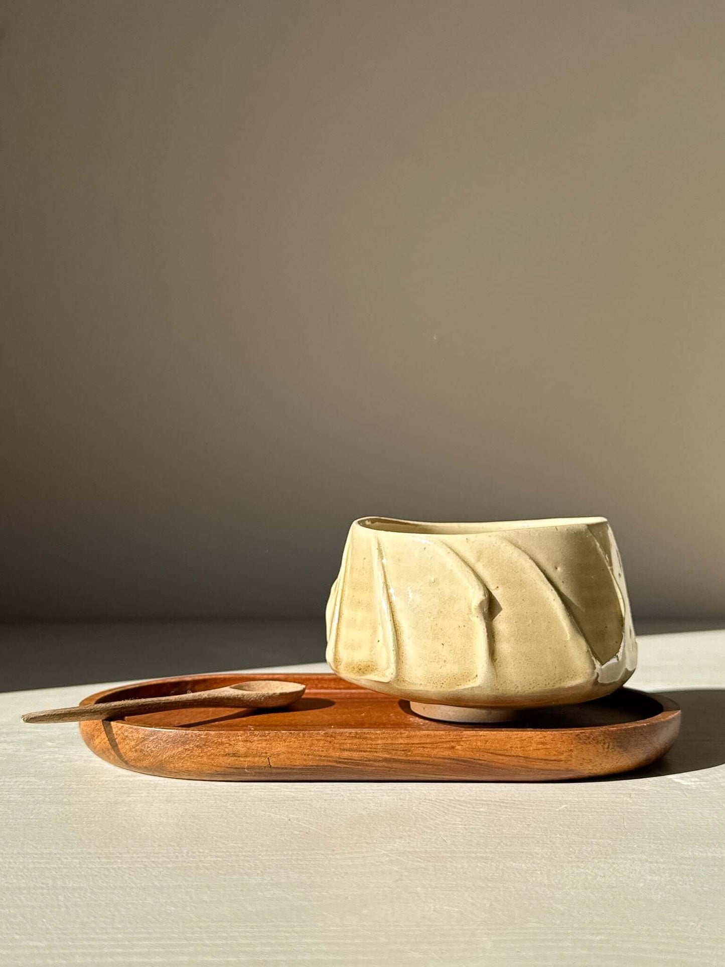 Yunomi Cup - Beige with textured glaze on a wooden tray in sunlight
