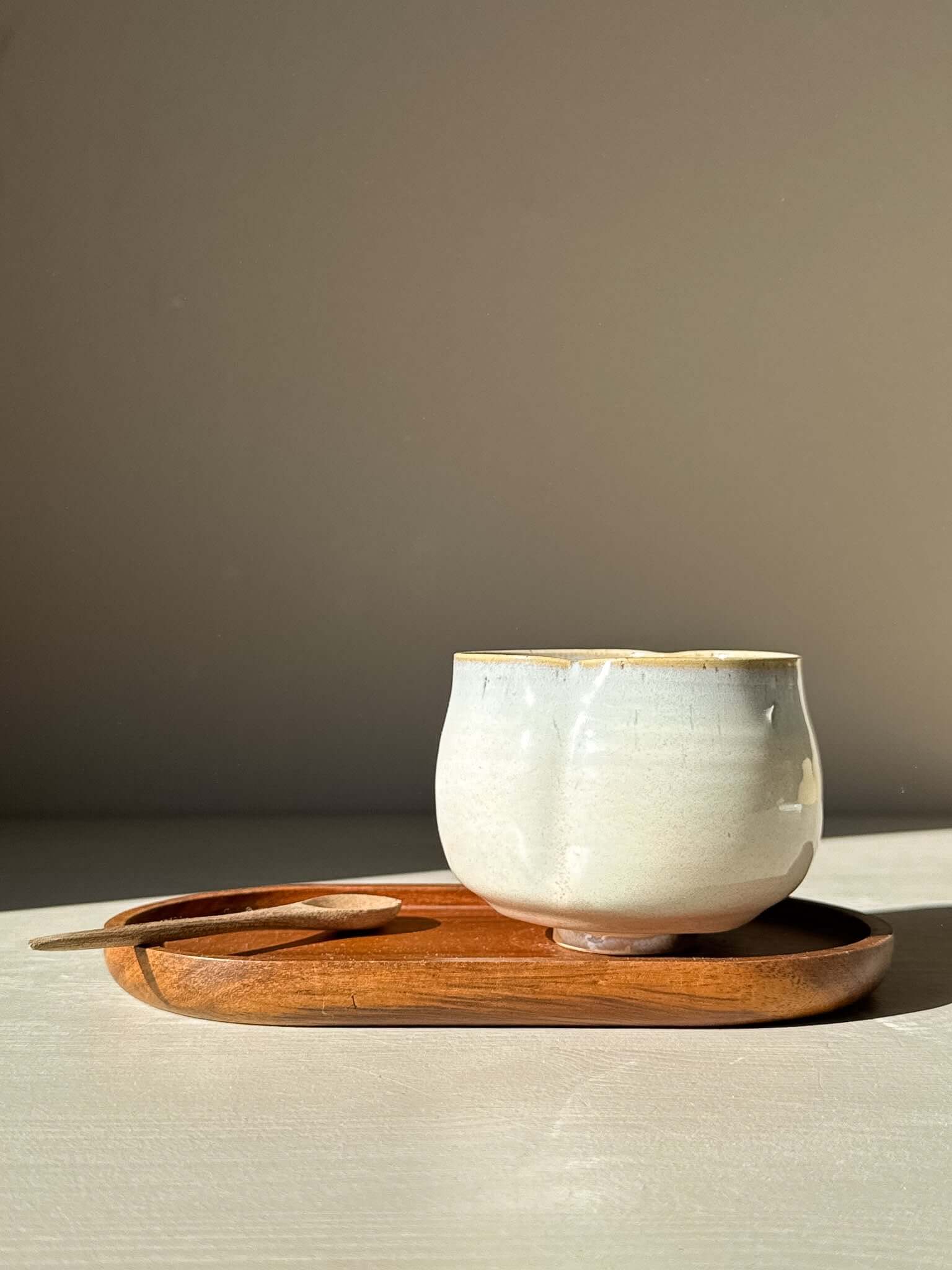 Yunomi Cup - Pale Blue on a wooden tray, showcasing its soft blue glaze and organic shape, perfect for tea enjoyment.